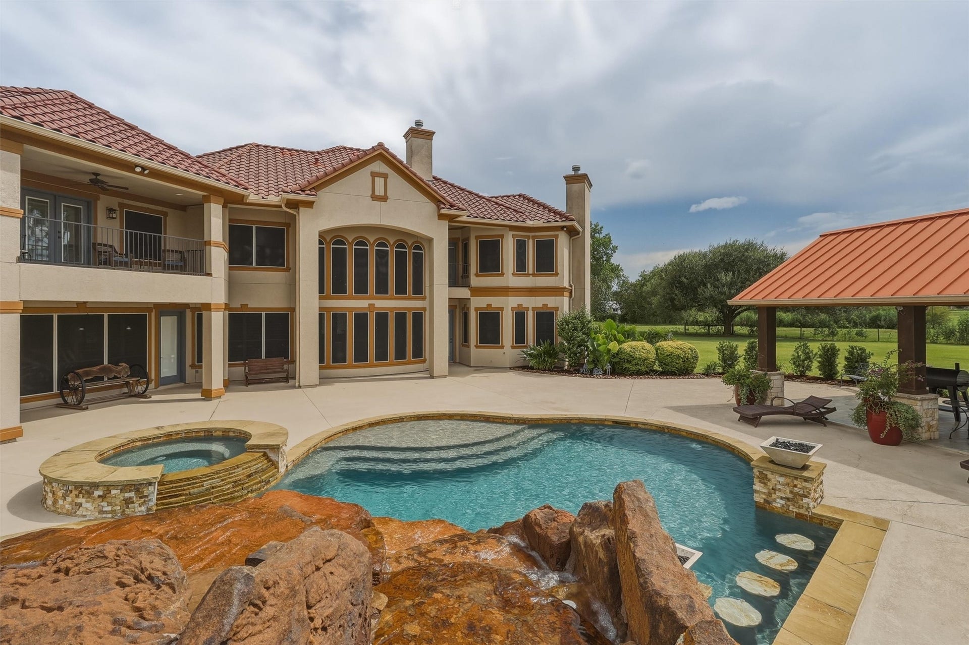 Step into your own private oasis featuring a resort-style pool with a raised spa and cascading rock waterfall. The expansive covered patio offers additional space for outdoor gatherings and relaxation.