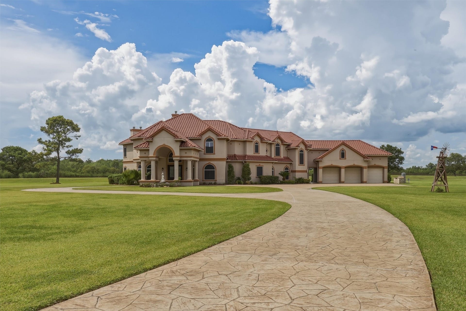 This stunning two-story stucco estate boasts a red tile roof, sweeping curved driveway, and a three-car attached garage. Manicured lawns and mature trees frame the gracefully arched front entry, creating a beautiful first impression.