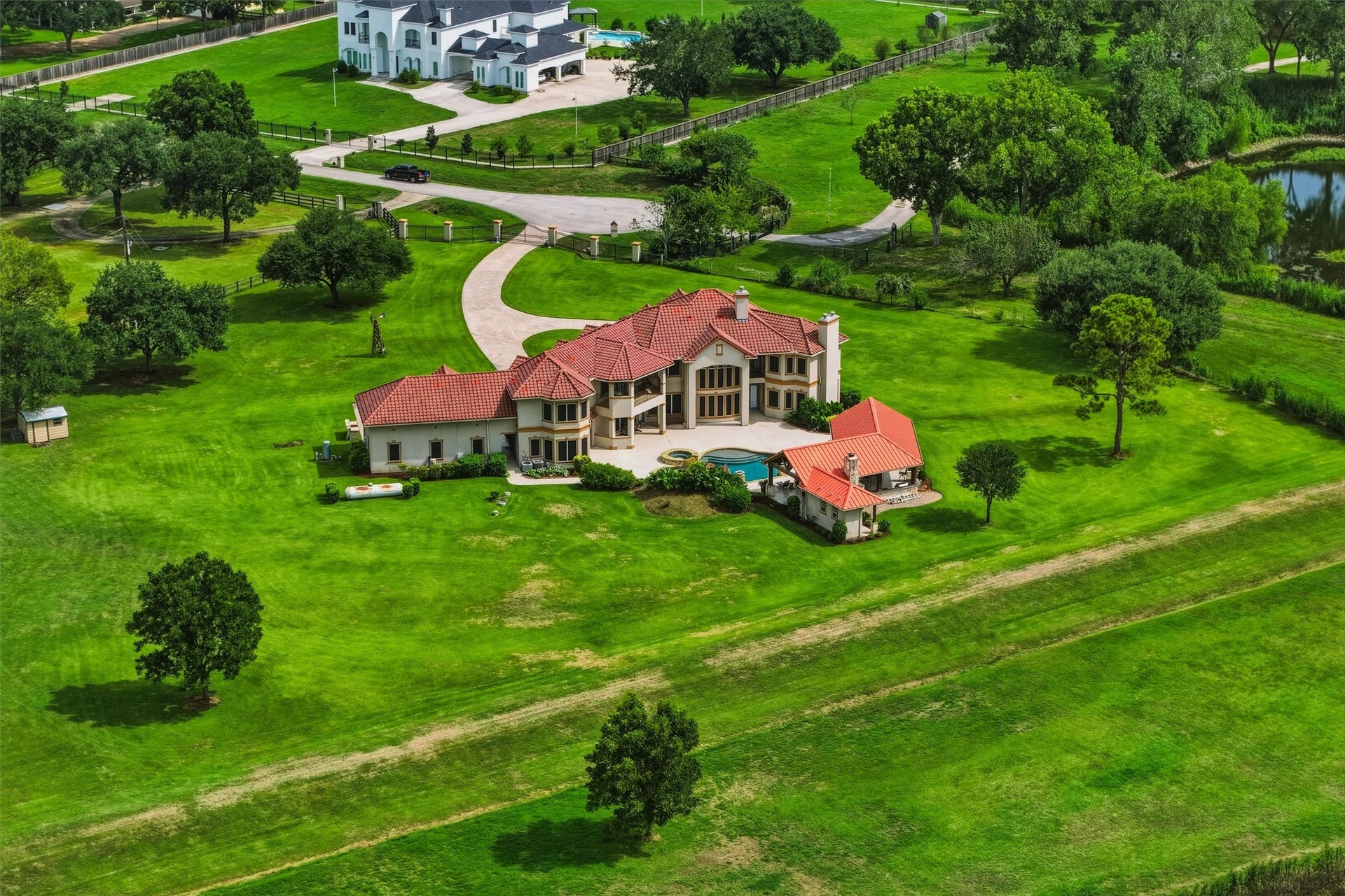 This breathtaking aerial perspective highlights the estate's generous acreage, sparkling pool, and covered outdoor living areas, all nestled within a serene and expansive natural landscape.