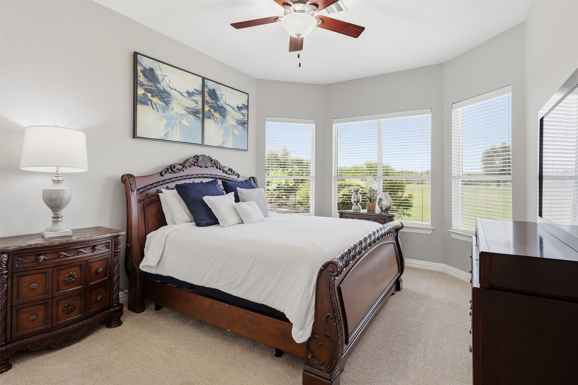 This spacious bedroom features a bay window with serene views of the surrounding landscape, plush carpeting, and a ceiling fan for year-round comfort. A beautifully carved sleigh bed adds timeless elegance.