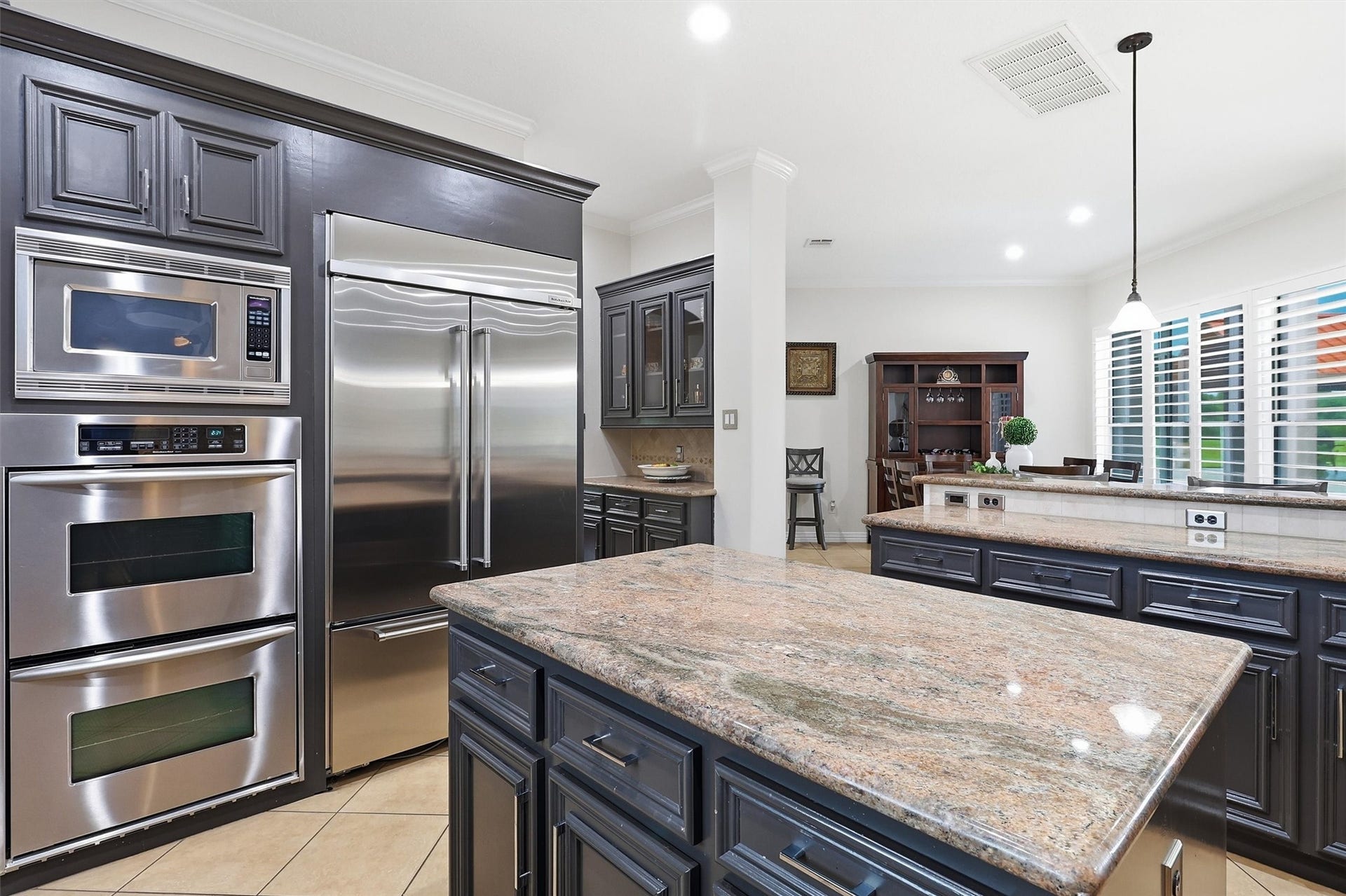 This kitchen is equipped with a built-in stainless refrigerator, double ovens, and a spacious granite island. The open layout flows effortlessly into the adjoining dining and living spaces.