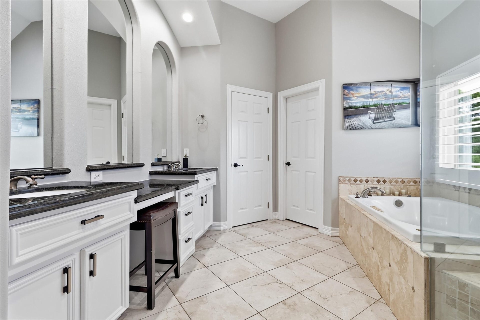 This spa-like primary bathroom offers dual vanities with granite countertops, an elevated jetted tub, and a private water closet. A full entry closet just off the space provides ample storage.