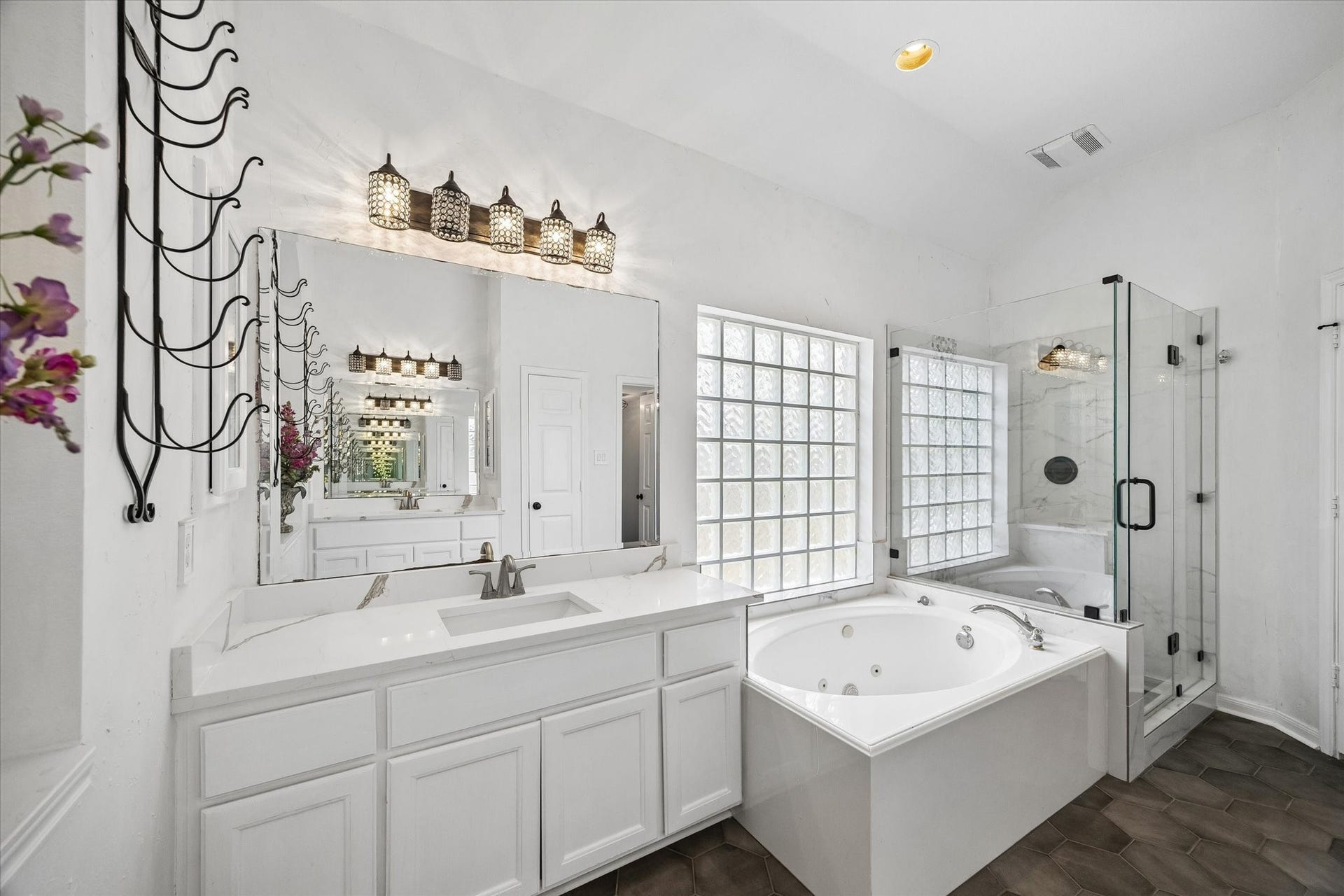 The elegant en suite bathroom features dual quartz vanities, a spacious walk-in stone shower, and a relaxing jetted soaking tub, creating a spa-like retreat.