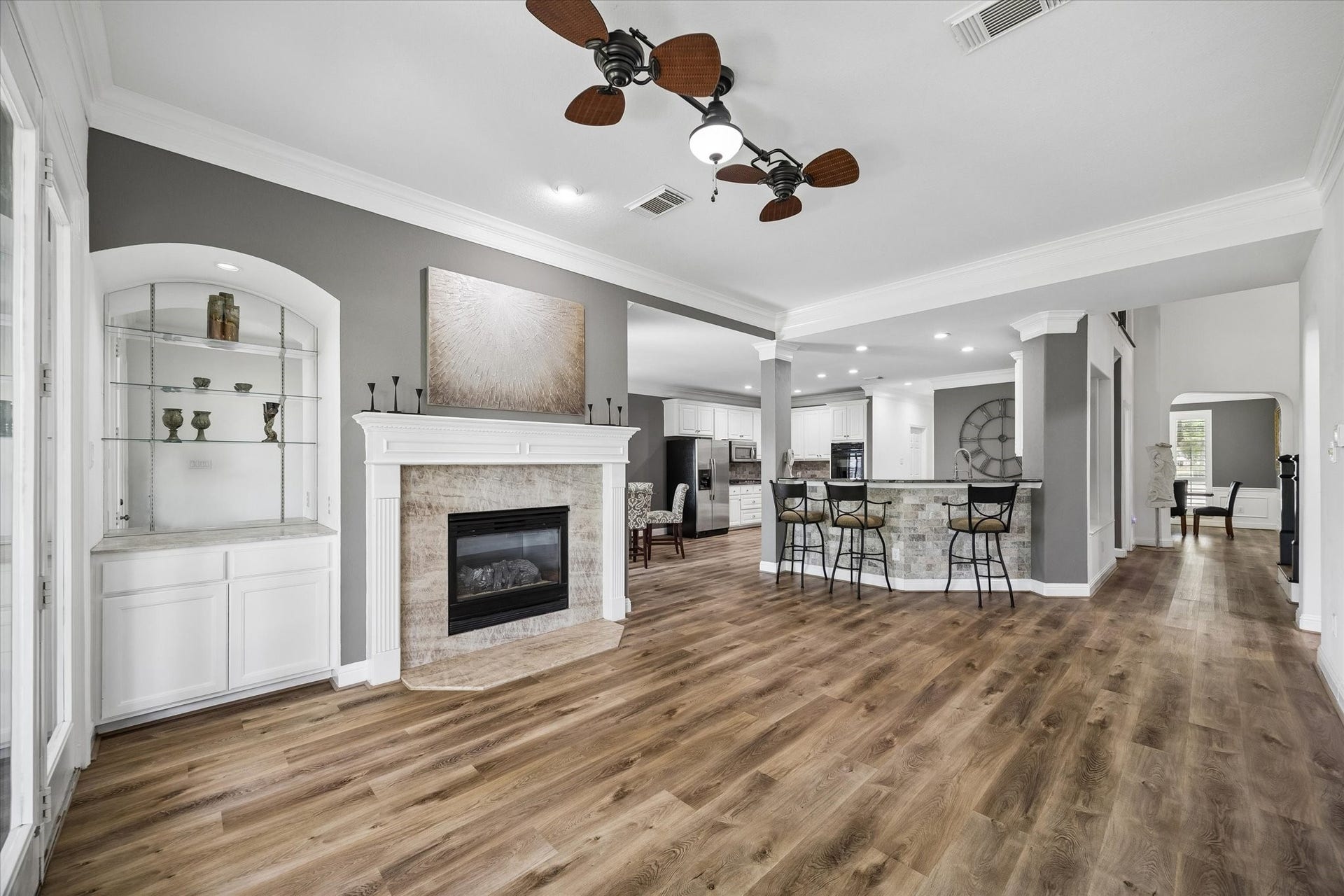 This open and inviting family room combines warmth and elegance with a gas fireplace, custom built-in shelving, and a breathtaking wall of windows that frames serene golf course views and creates a seamless connection to the outdoors.