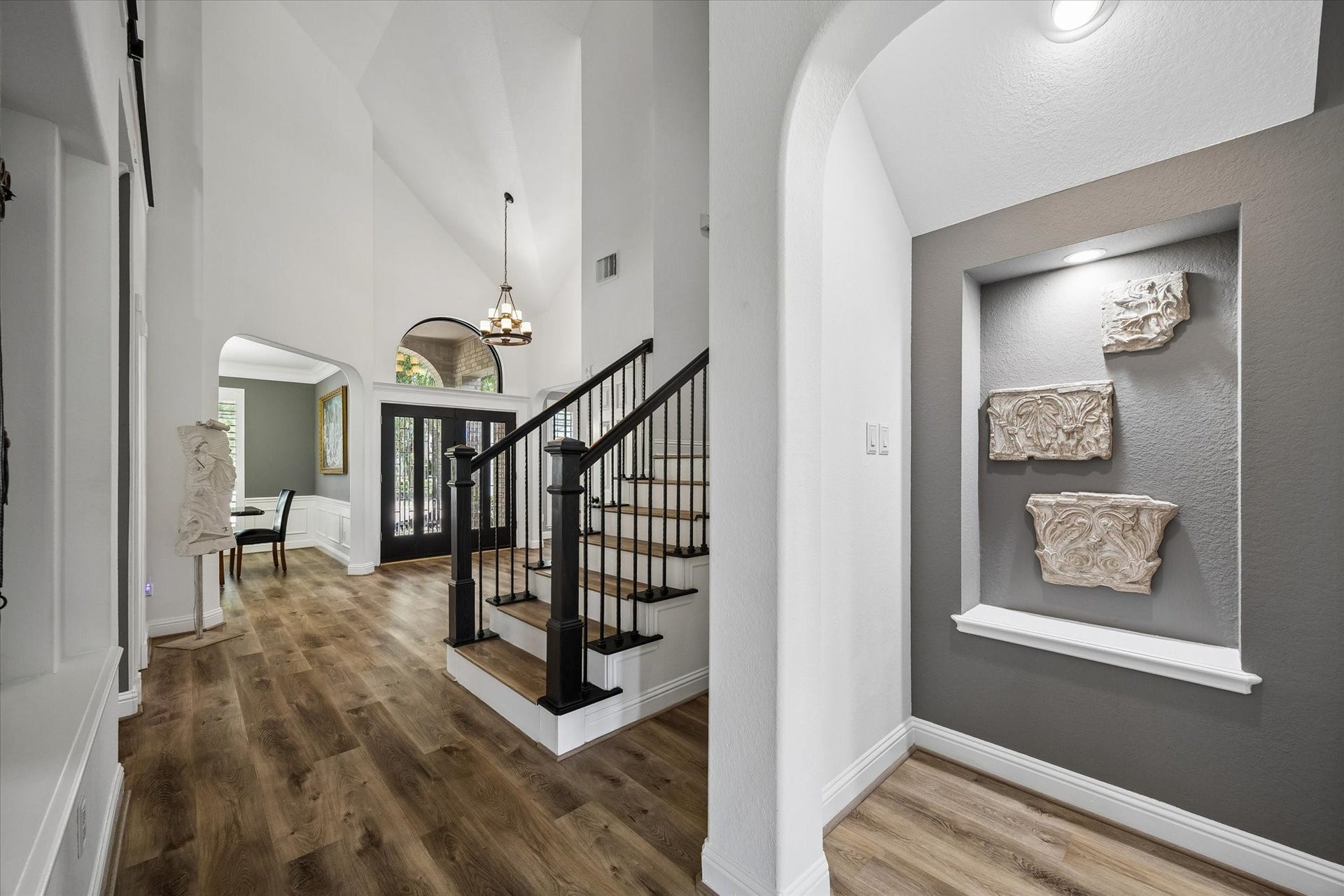 Step into a grand foyer that showcases the home's open-concept design, with a private home office or study to one side, an elegant formal dining room to the other, and custom plantation shutters adding timeless style throughout.