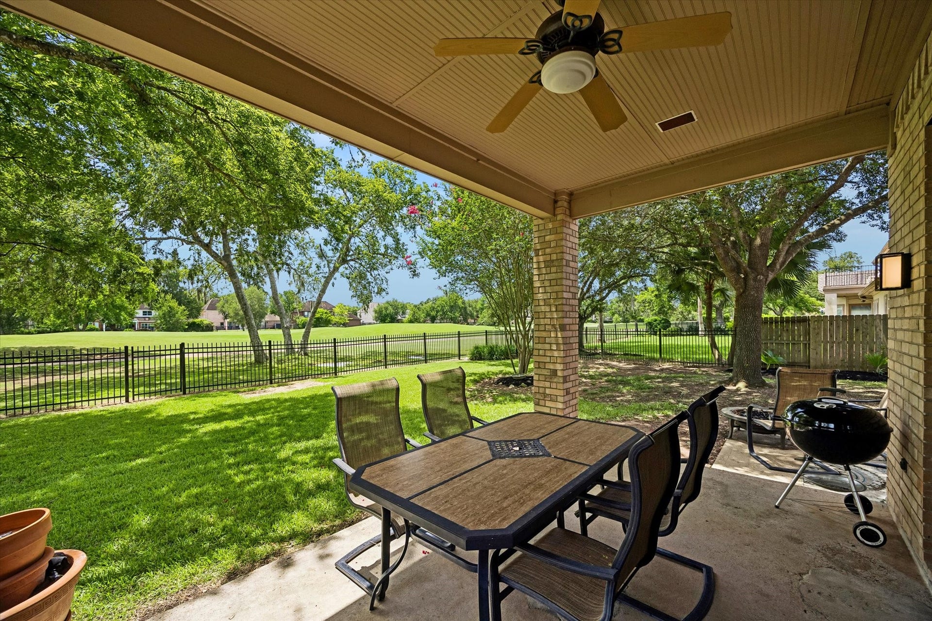 Designed for both relaxation and entertaining, the spacious backyard features an expansive patio, mature shade trees, and a wrought iron fence that frames picturesque golf course views.