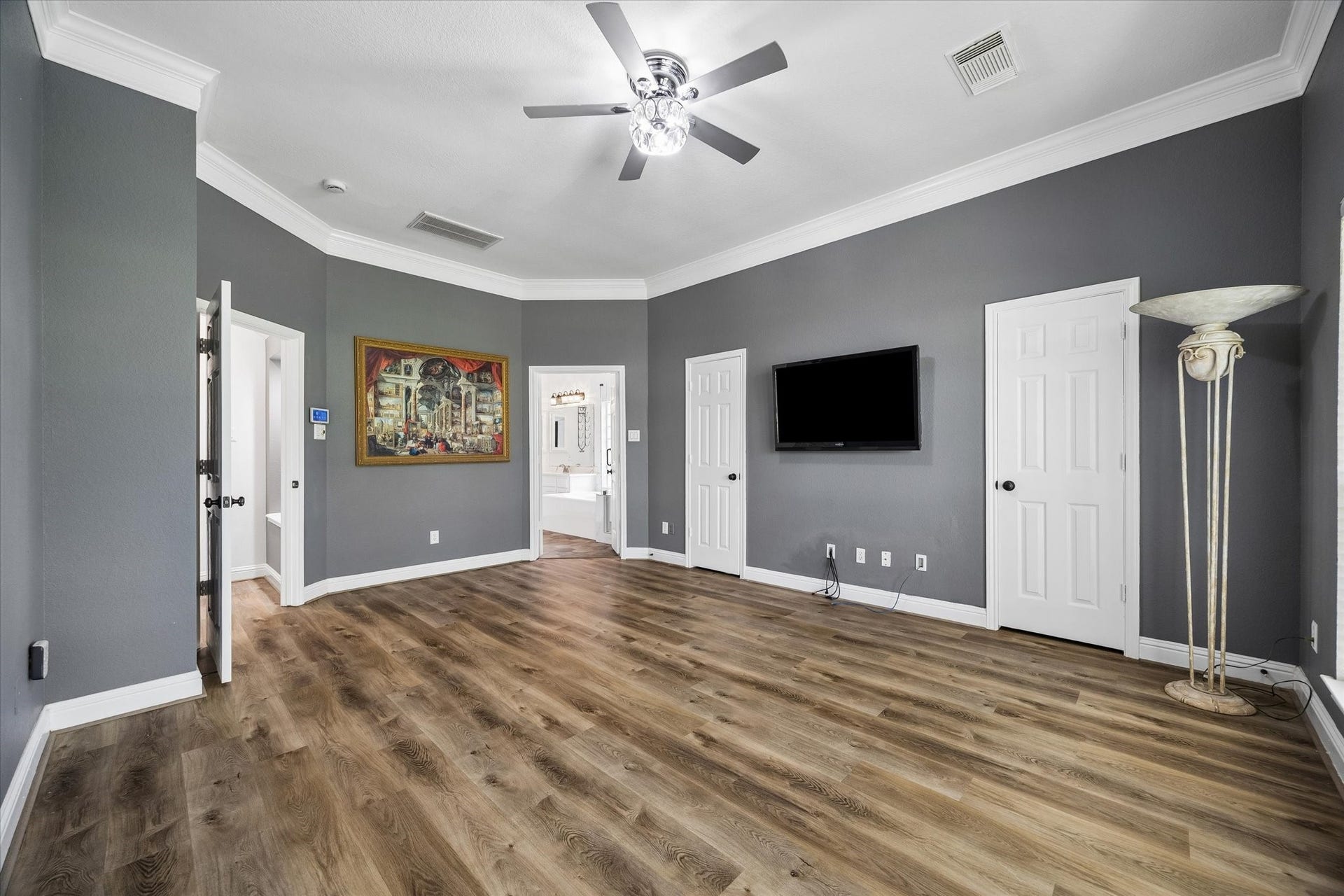 The luxurious primary suite is bathed in natural light from a dramatic wall of windows and features separate his-and-hers walk-in closets, creating a private retreat that is both elegant and functional.