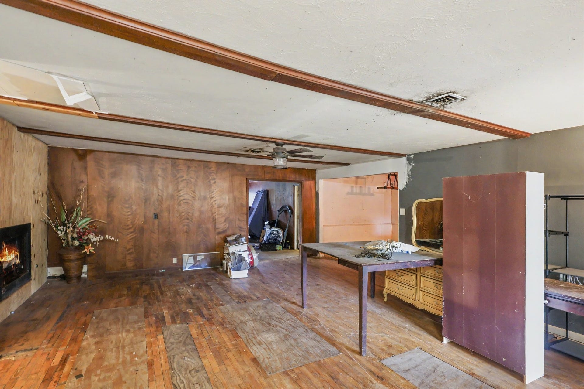 11 Craig Street, Baytown, TX 77521 Living area featuring a fireplace, wood paneling and ceiling beams. Renovations needed.