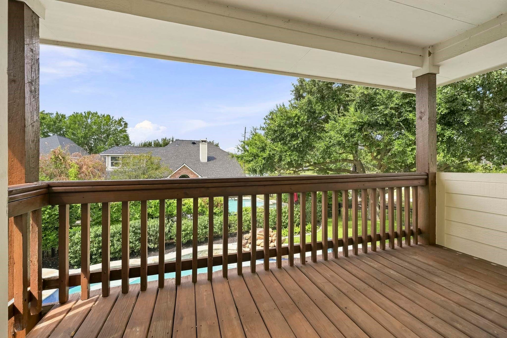5702 Misty Island Court, Katy, TX 77494 Spacious covered balcony offering serene views of lush greenery and a glimpse of neighboring homes, perfect for relaxing or entertaining.