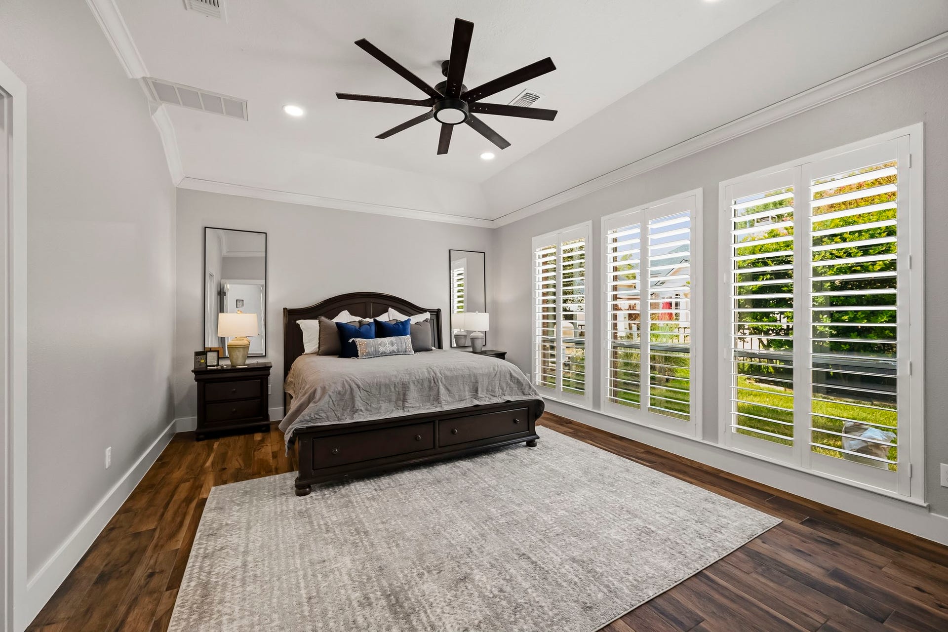 5702 Misty Island Court, Katy, TX 77494 Spacious bedroom featuring elegant hardwood floors, large windows with plantation shutters, and a stylish ceiling fan, creating a bright and inviting atmosphere.