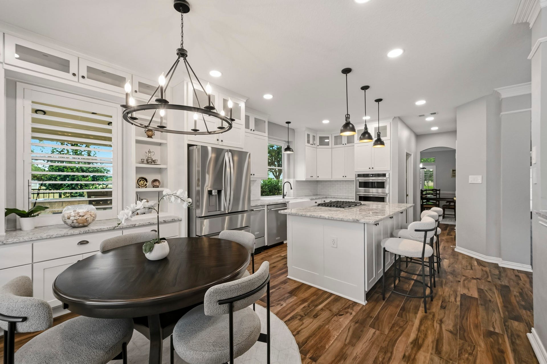 5702 Misty Island Court, Katy, TX 77494 Stunning kitchen featuring sleek white cabinetry, stainless steel appliances, and a large center island with bar seating. The open layout is enhanced by elegant pendant lighting and rich hardwood floors, creating a warm, inviting atmosphere perfect for cooking and entertaining.