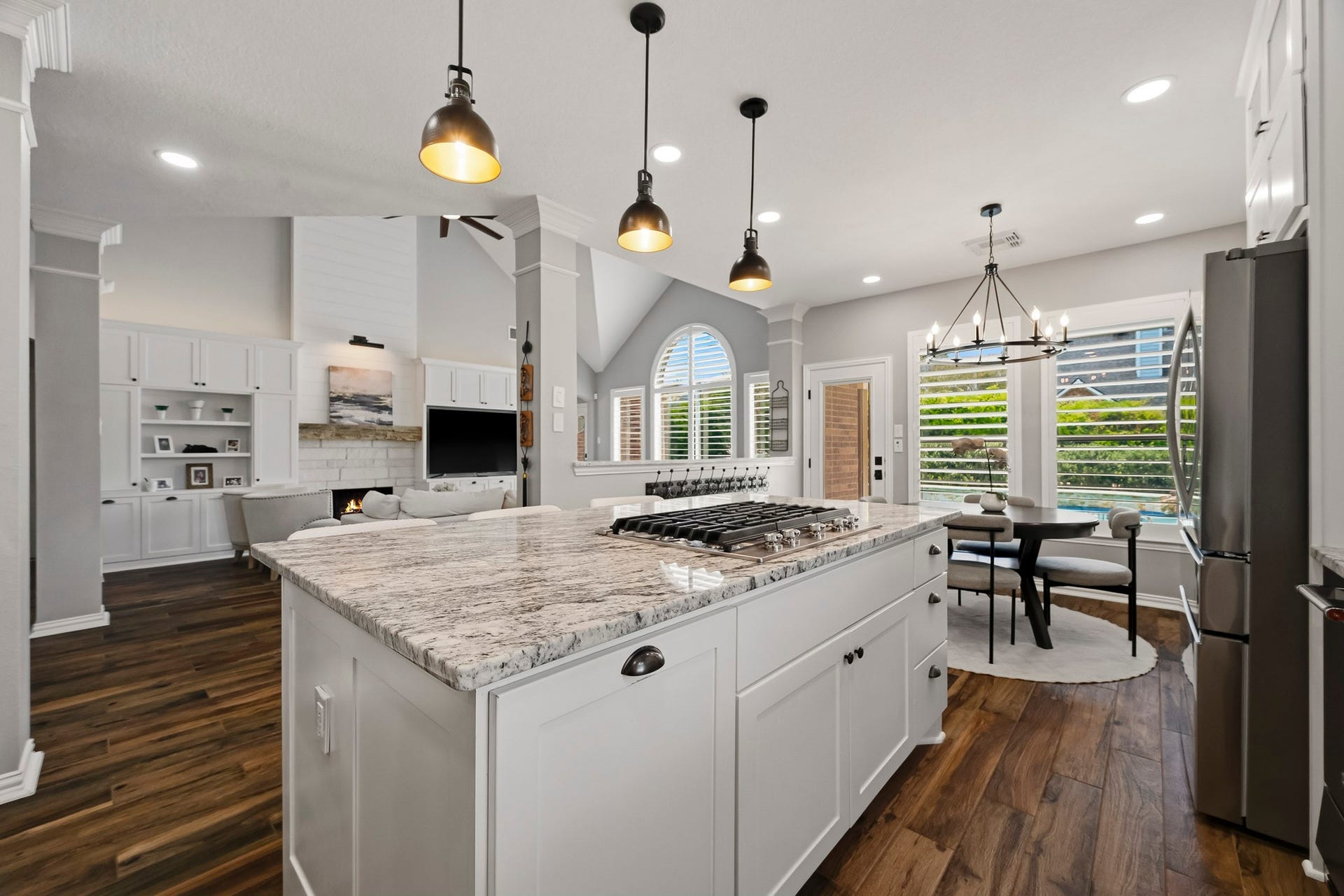 5702 Misty Island Court, Katy, TX 77494 Bright and inviting open-concept kitchen and living area with a spacious island, elegant pendant lighting, and a cozy fireplace, perfect for entertaining.