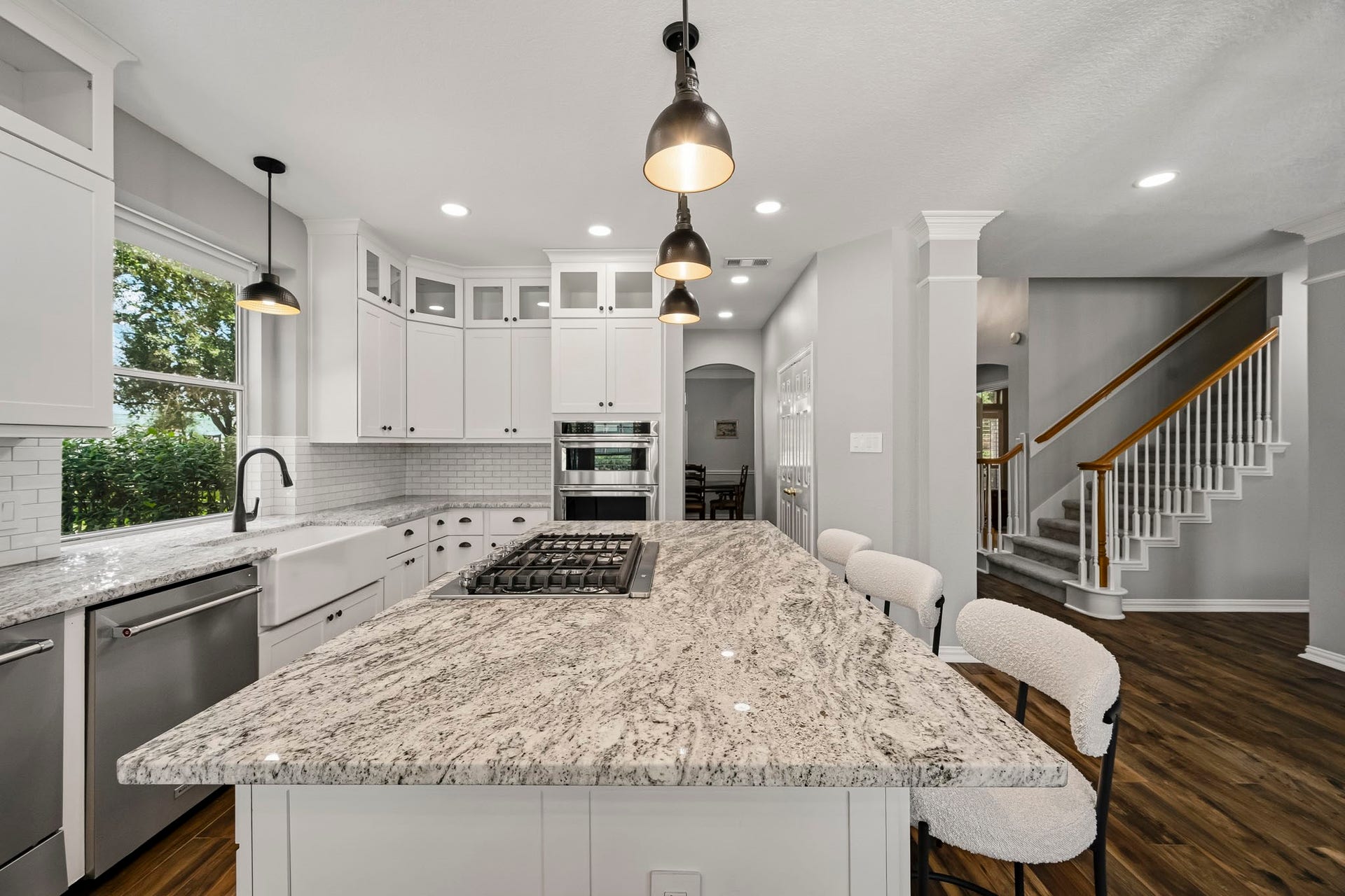 5702 Misty Island Court, Katy, TX 77494 Elegant kitchen featuring a spacious granite island with a built-in cooktop, complemented by sleek white cabinetry and modern pendant lighting.