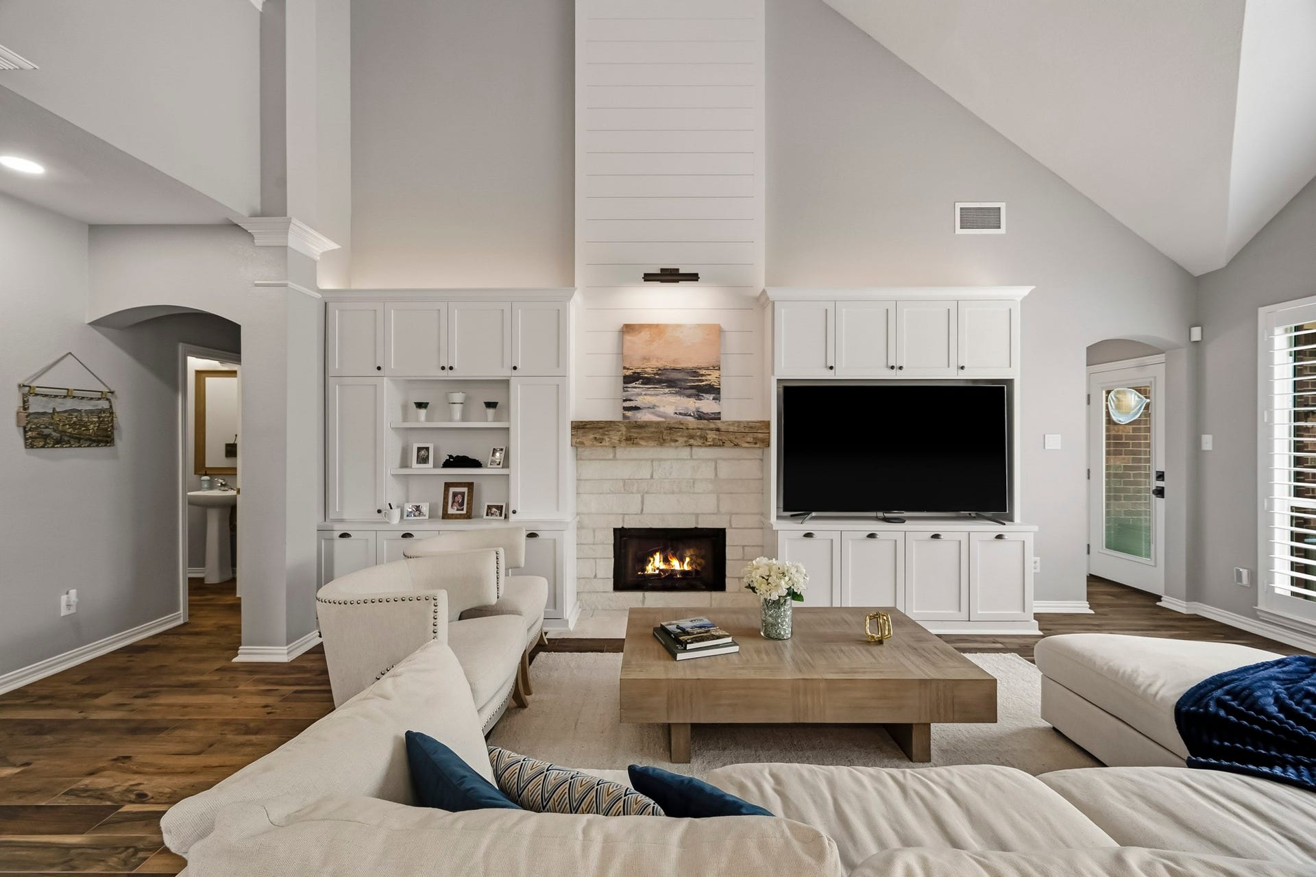5702 Misty Island Court, Katy, TX 77494 Spacious living room with high ceilings features a cozy fireplace flanked by custom built-ins, a large TV, and elegant wood flooring, creating a welcoming and stylish atmosphere.