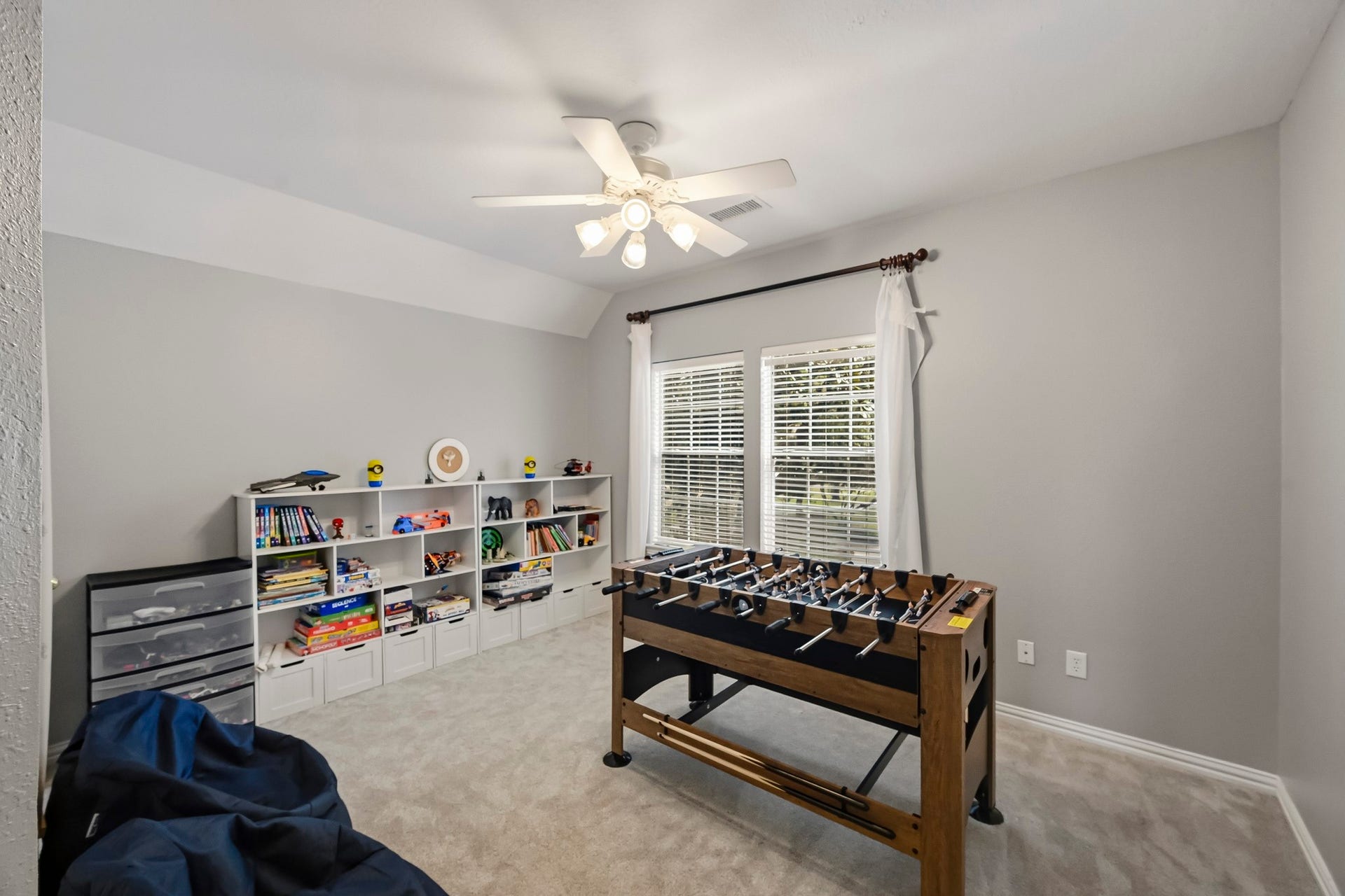 5702 Misty Island Court, Katy, TX 77494 Bright and spacious game room featuring a foosball table, ample shelving for books and toys, and a ceiling fan for comfort.