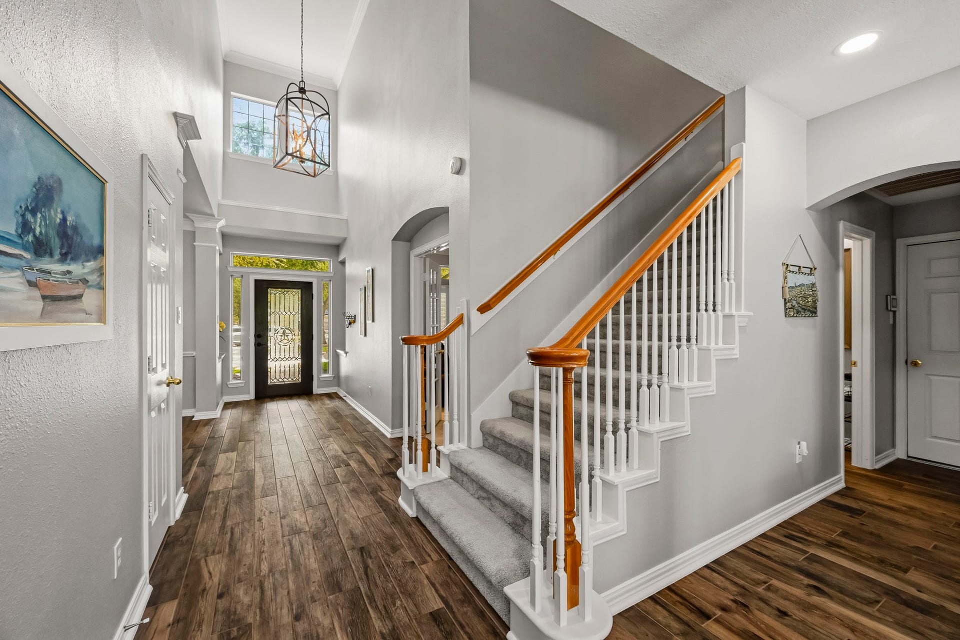 5702 Misty Island Court, Katy, TX 77494 A grand, welcoming foyer with high ceilings features elegant wood flooring, a stylish staircase, and abundant natural light through large windows and a decorative front door.