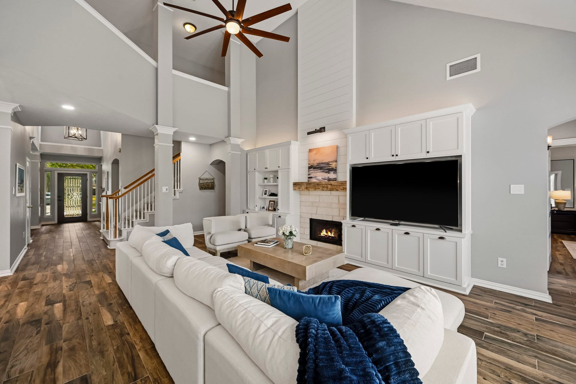 5702 Misty Island Court, Katy, TX 77494 Spacious living room with high ceilings, elegant wood flooring, and a cozy fireplace. The open layout features built-in cabinetry and ample natural light, creating a warm and inviting atmosphere.