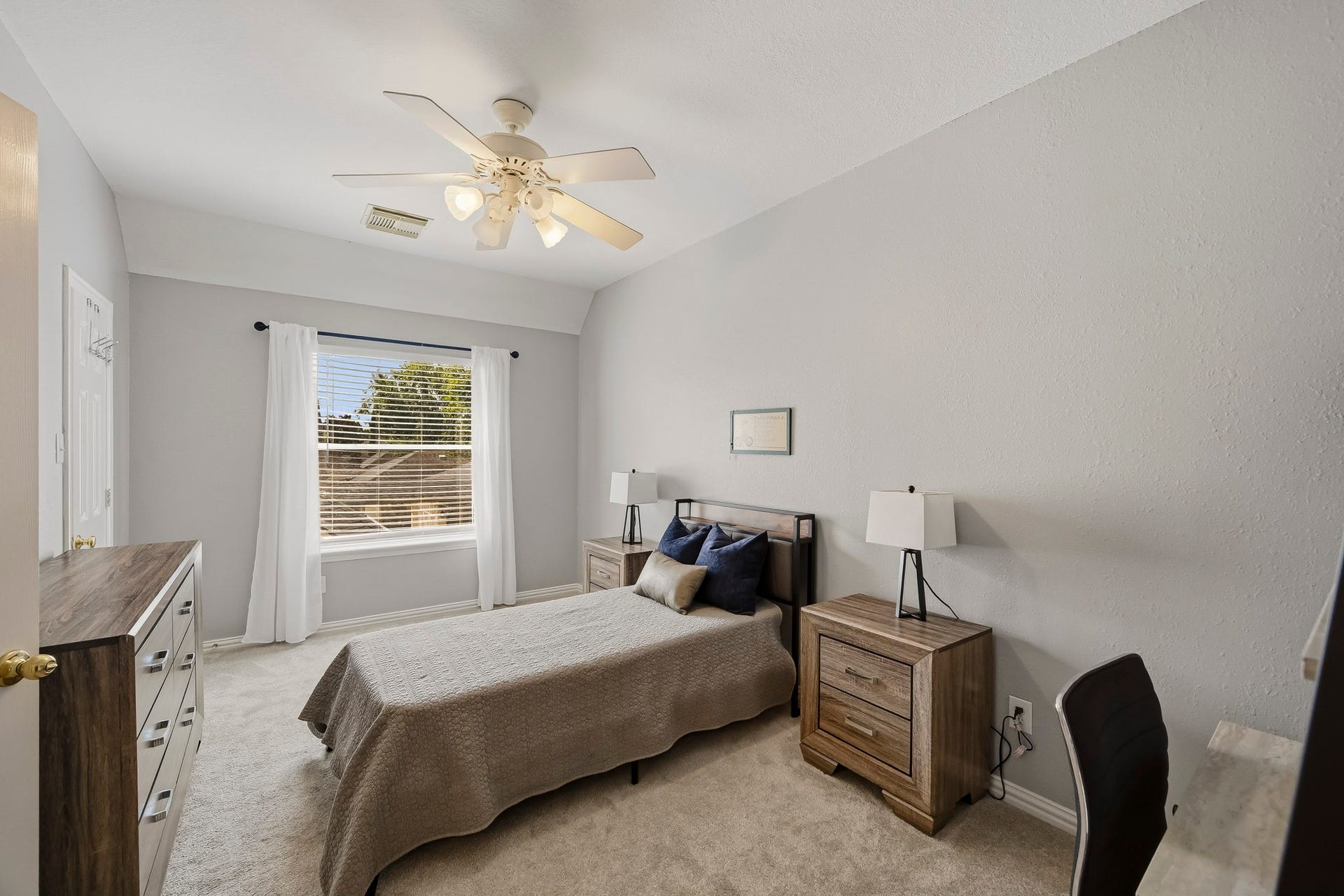 5702 Misty Island Court, Katy, TX 77494 Bright and inviting bedroom featuring soft carpet, a ceiling fan, and ample natural light from a large window with elegant drapes.