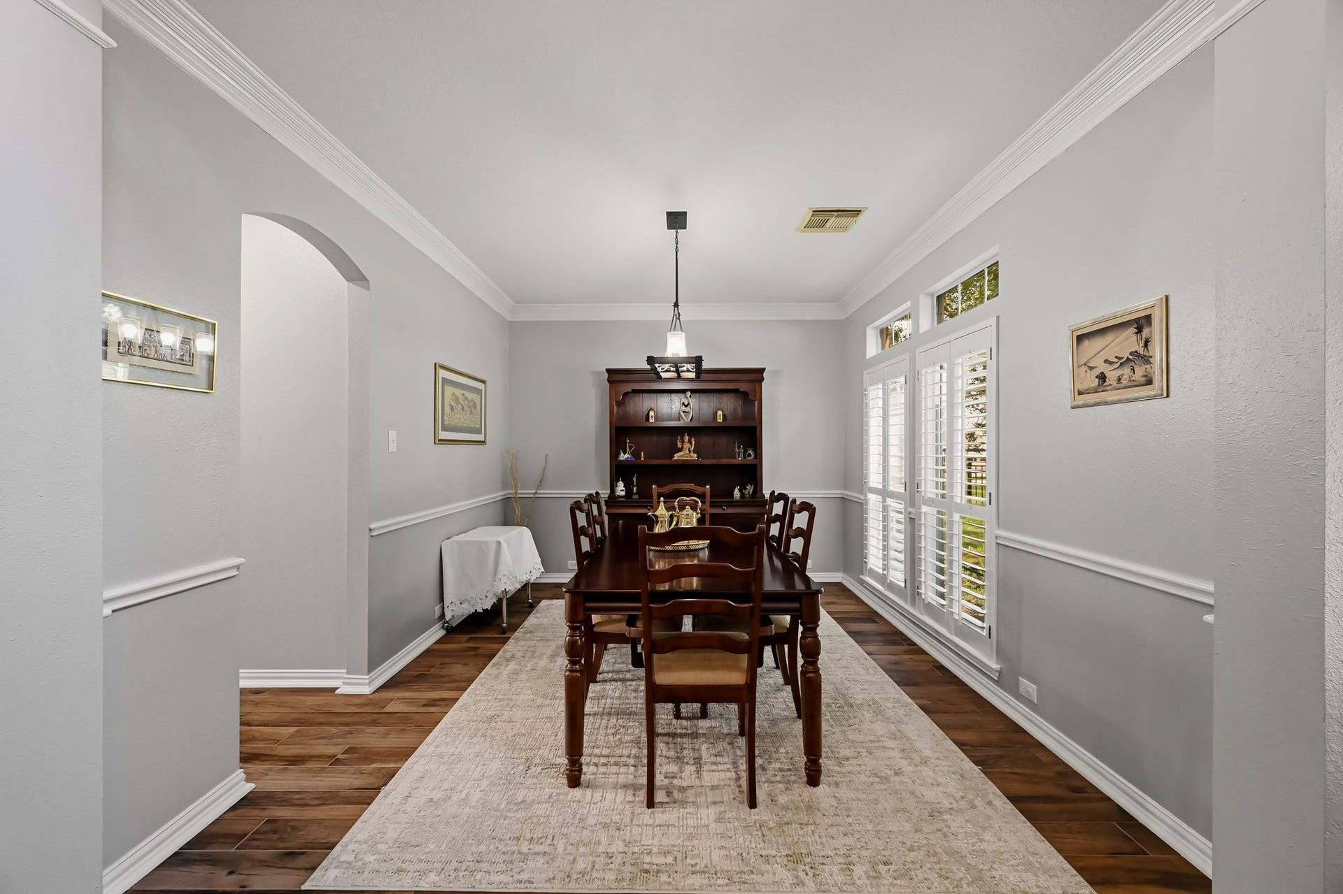 5702 Misty Island Court, Katy, TX 77494 Elegant dining room with rich hardwood floors, a classic wooden table, and abundant natural light streaming through large windows with plantation shutters.
