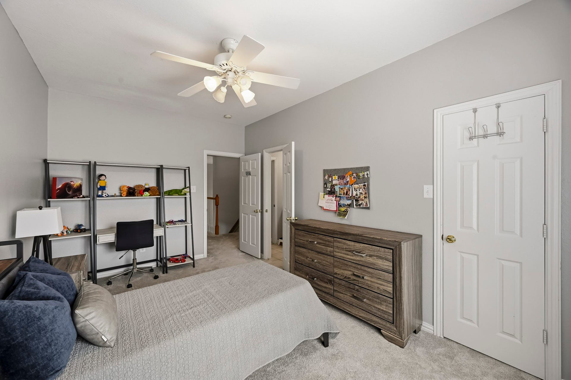 5702 Misty Island Court, Katy, TX 77494 Cozy bedroom featuring neutral tones, a ceiling fan, and ample storage with a modern dresser and shelving unit. Perfect for relaxation and study.