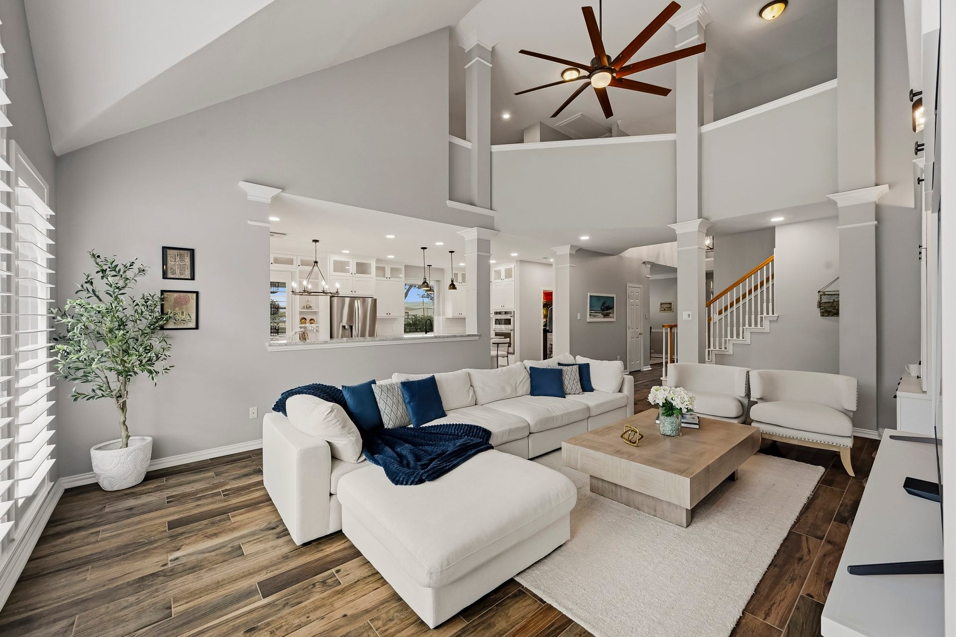5702 Misty Island Court, Katy, TX 77494 Spacious living area with vaulted ceilings, modern open layout, and elegant wood flooring. The room is beautifully lit with large windows and features a cozy sectional sofa, stylish ceiling fan, and direct access to the kitchen, perfect for entertaining.