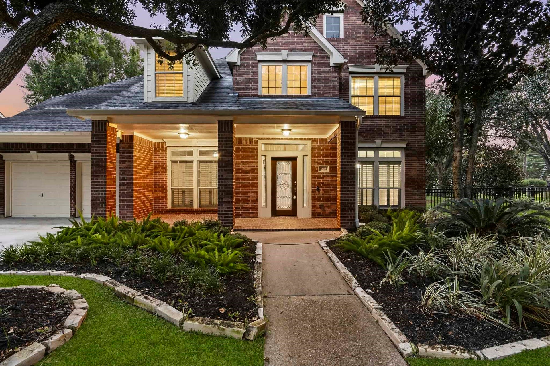 5702 Misty Island Court, Katy, TX 77494 Spacious living room with vaulted ceilings, elegant built-in cabinetry, and a cozy fireplace. Large windows offer abundant natural light and views of the outdoor pool.