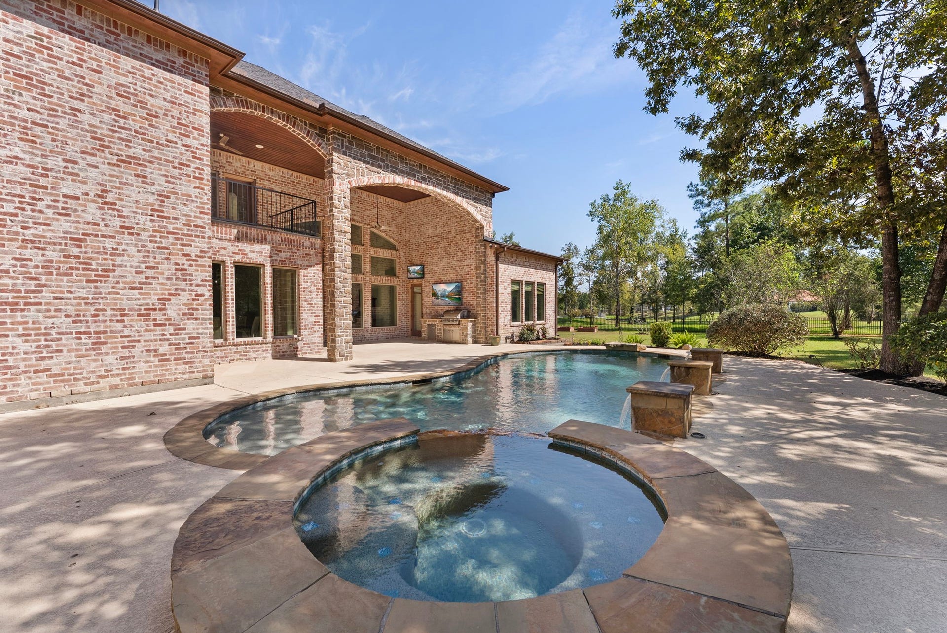 27507 Hunter Creek Court, Spring, TX 77386 Swimming pool and raised spa framed by the home's rear brick elevation and mature landscaping.