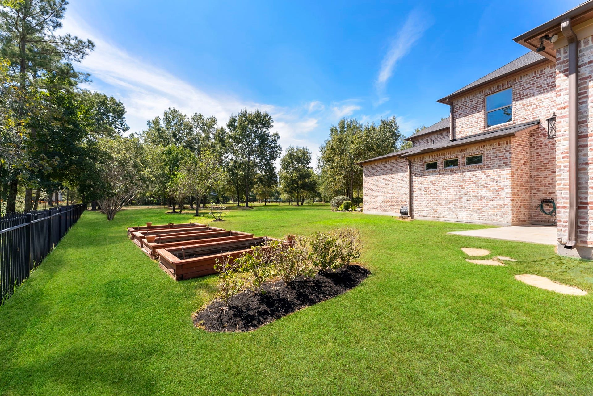 27507 Hunter Creek Court, Spring, TX 77386 Side yard with raised garden beds, manicured lawn and mature landscaping.