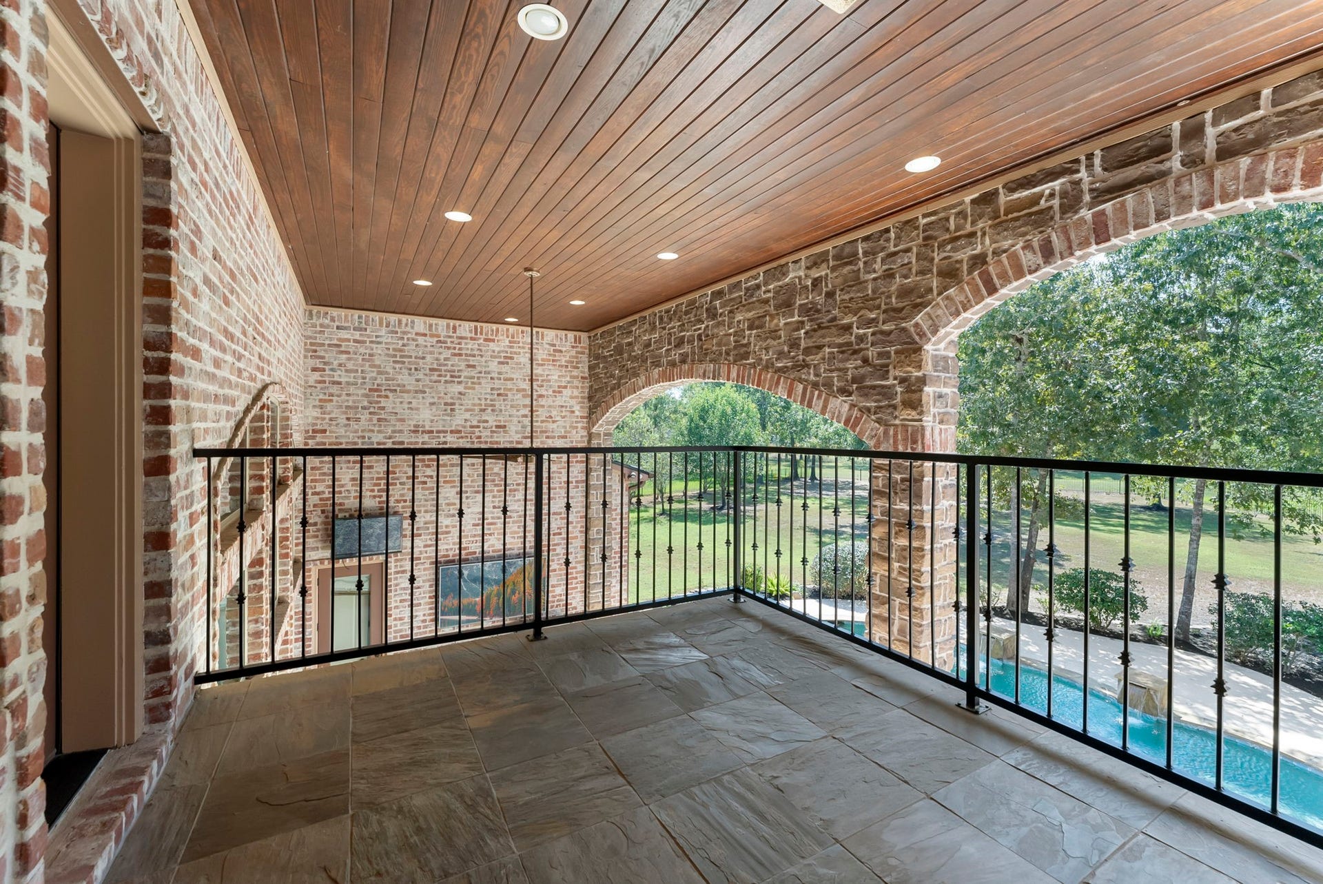 27507 Hunter Creek Court, Spring, TX 77386 Covered upper balcony with brick arches, tile flooring and wrought-iron railing.