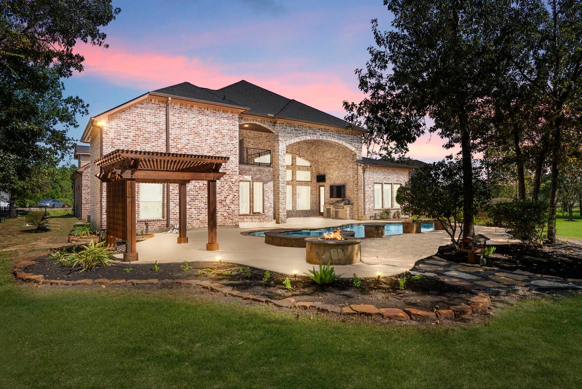 27507 Hunter Creek Court, Spring, TX 77386 Twilight backyard view highlighting the pool, covered patio, pergola, landscaping and poolside fire feature.
