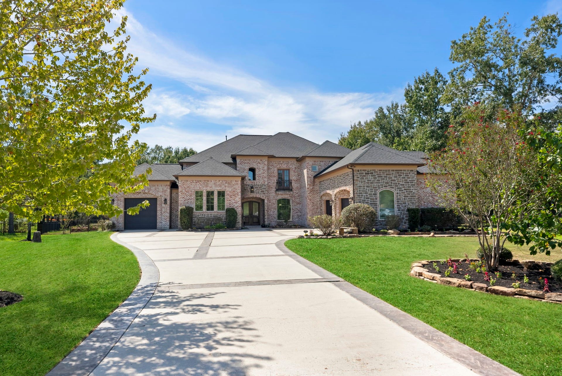 27507 Hunter Creek Court, Spring, TX 77386 Daytime front elevation with expansive curved driveway, landscaped lawn and mature trees.