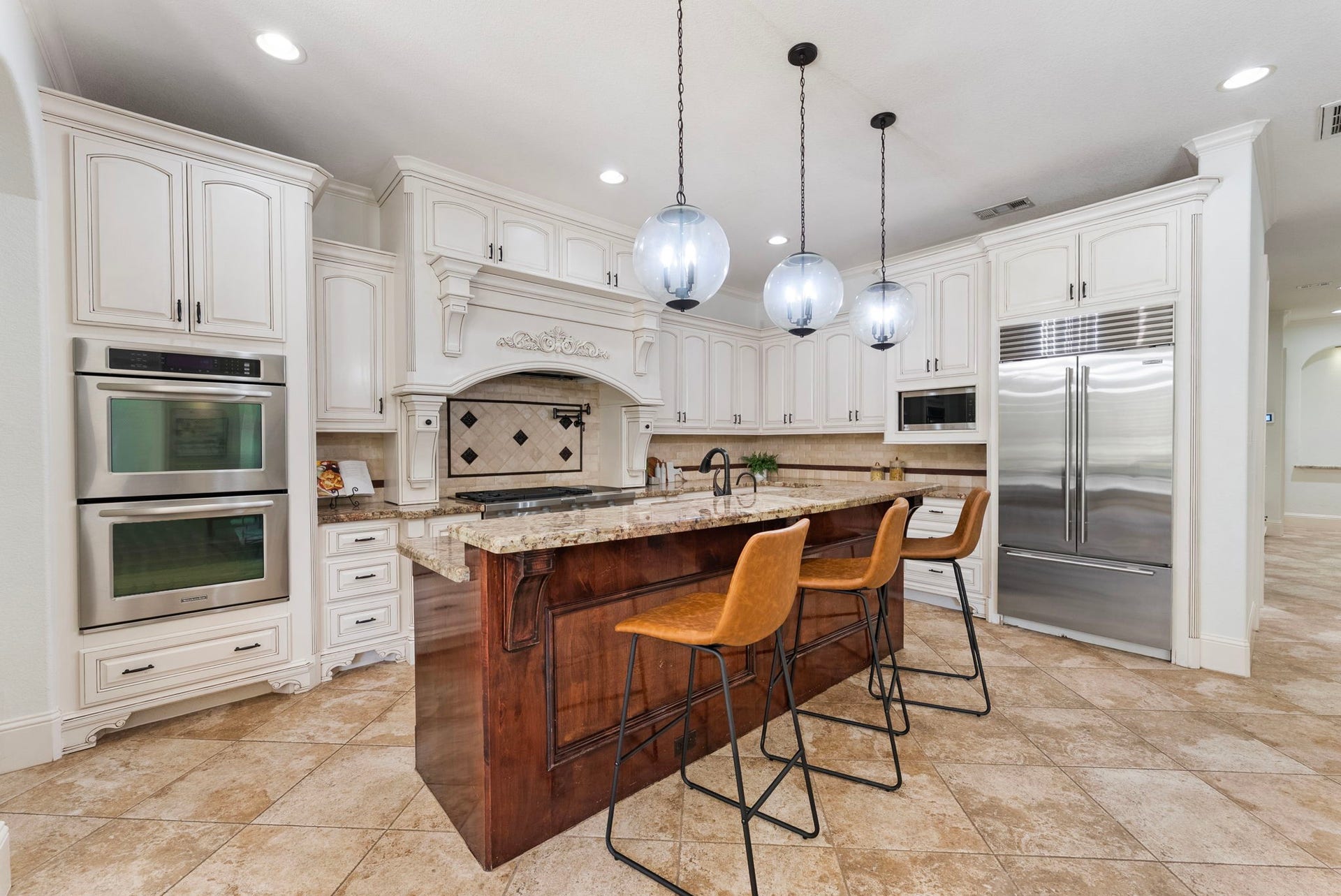 27507 Hunter Creek Court, Spring, TX 77386 Kitchen featuring a large island, detailed cabinetry, double ovens, cooktop and stainless-steel refrigerator.