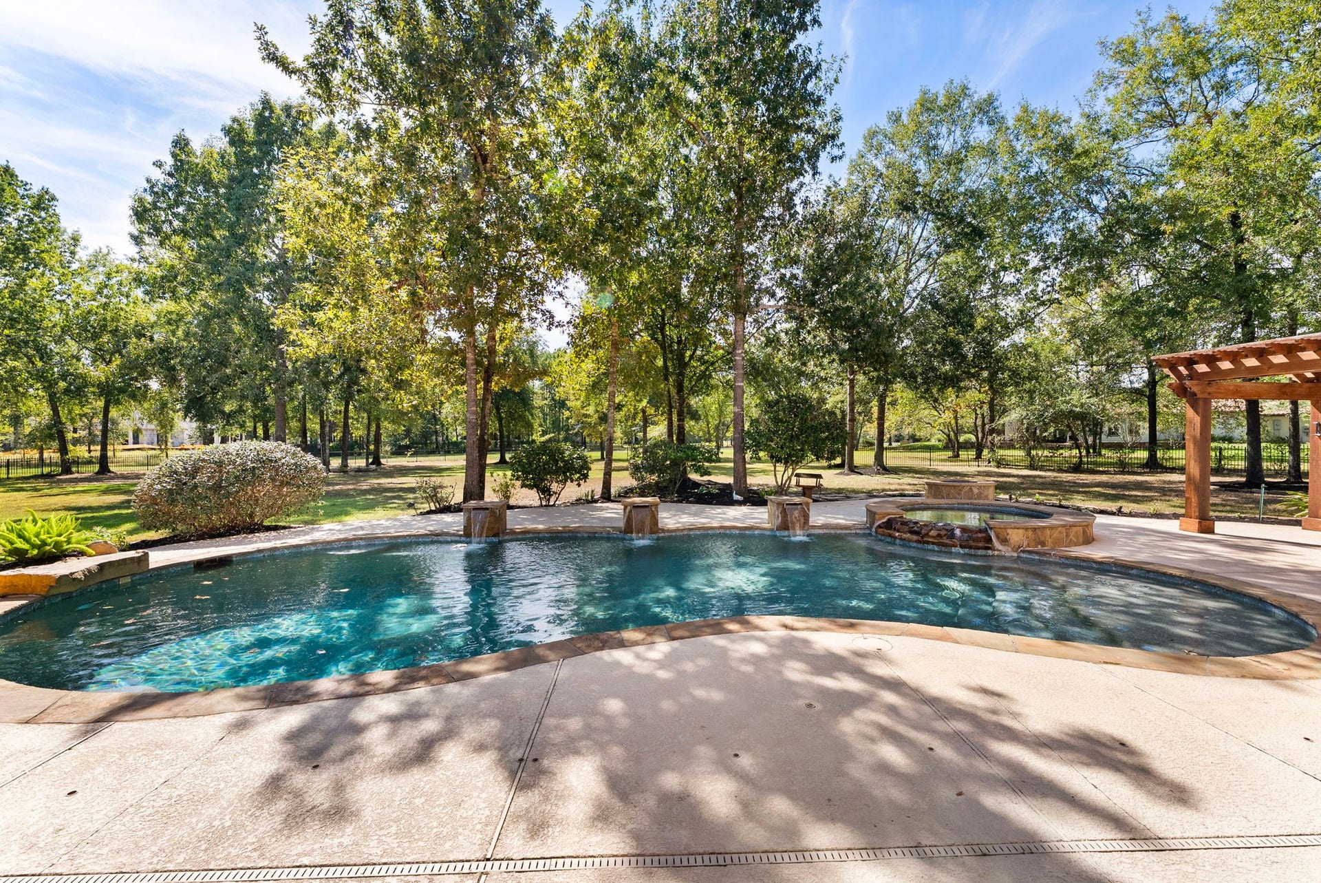 27507 Hunter Creek Court, Spring, TX 77386 Wide view of the swimming pool surrounded by extensive decking and mature trees.