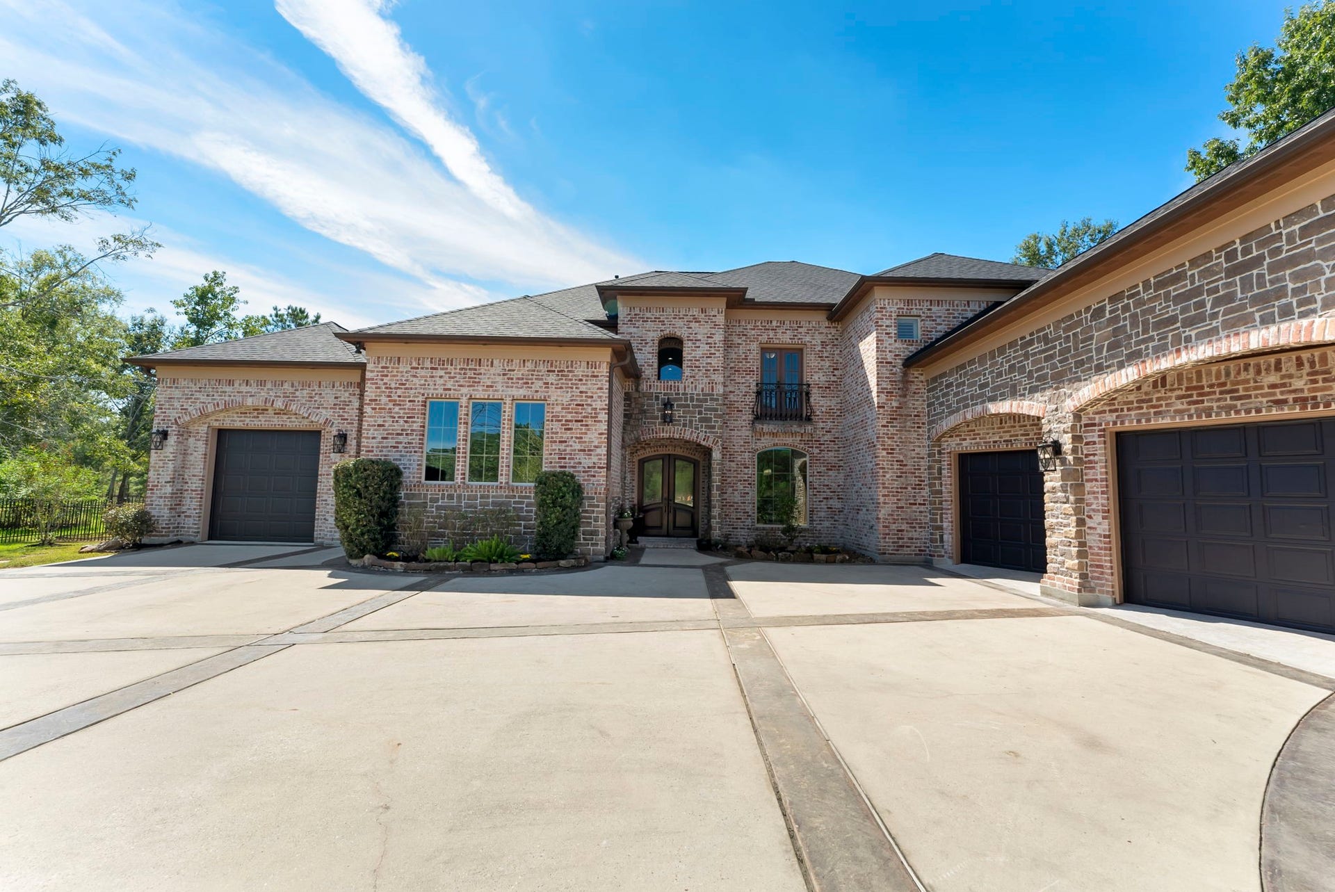 27507 Hunter Creek Court, Spring, TX 77386 Front motor court showcasing the brick-and-stone architecture and multiple garage bays.
