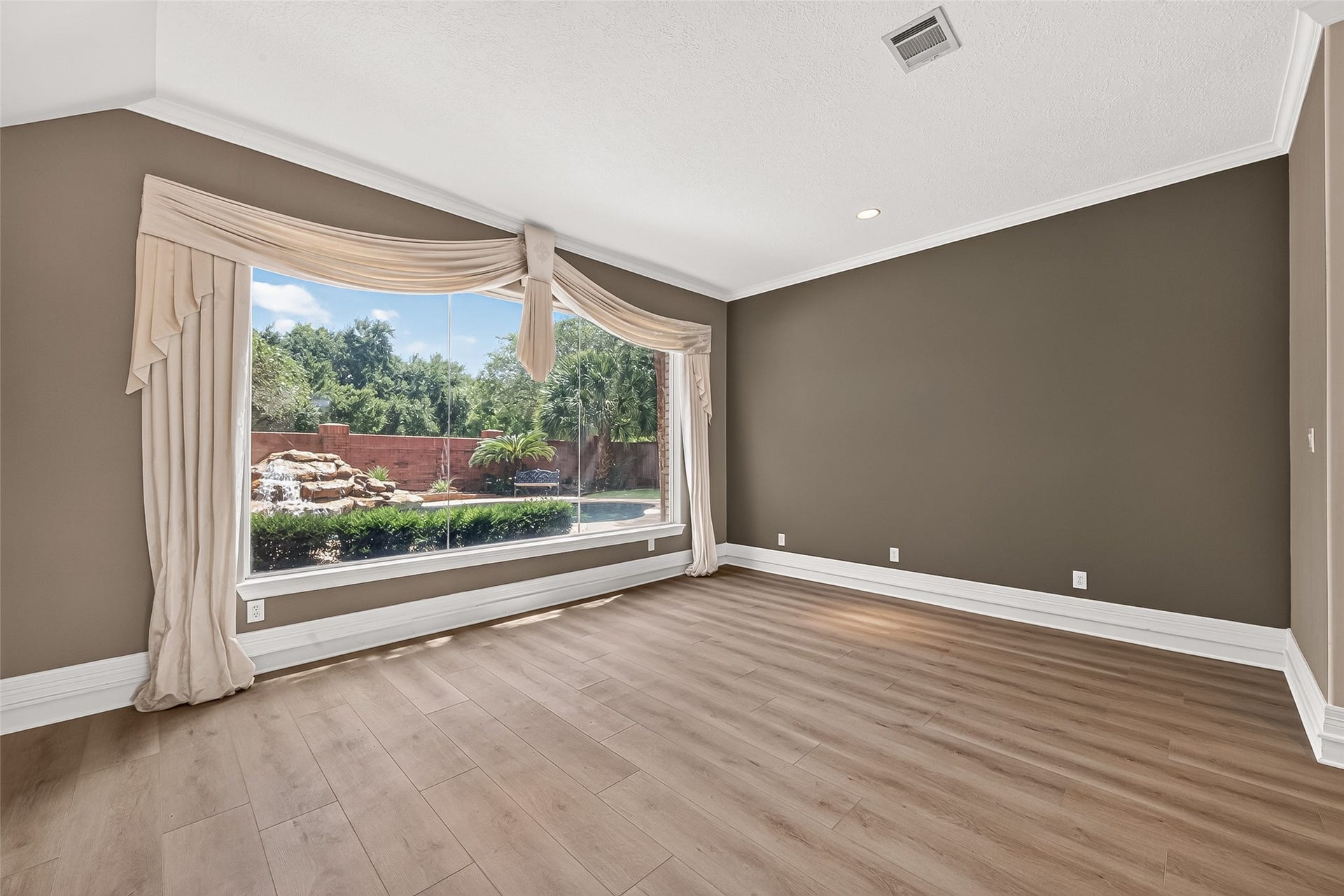 63 Harbor View Drive, Sugar Land, TX 77479 Formal sitting room with beautiful LVP flooring and huge large windows offering a stunning view of the pool/spa and waterfall feature