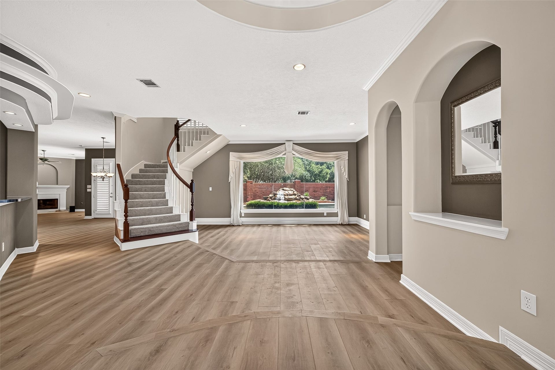 63 Harbor View Drive, Sugar Land, TX 77479 Amazing open-concept floor plan featuring a grand staircase, stylish arched openings, and a large window offering a stunning view of the backyard oasis