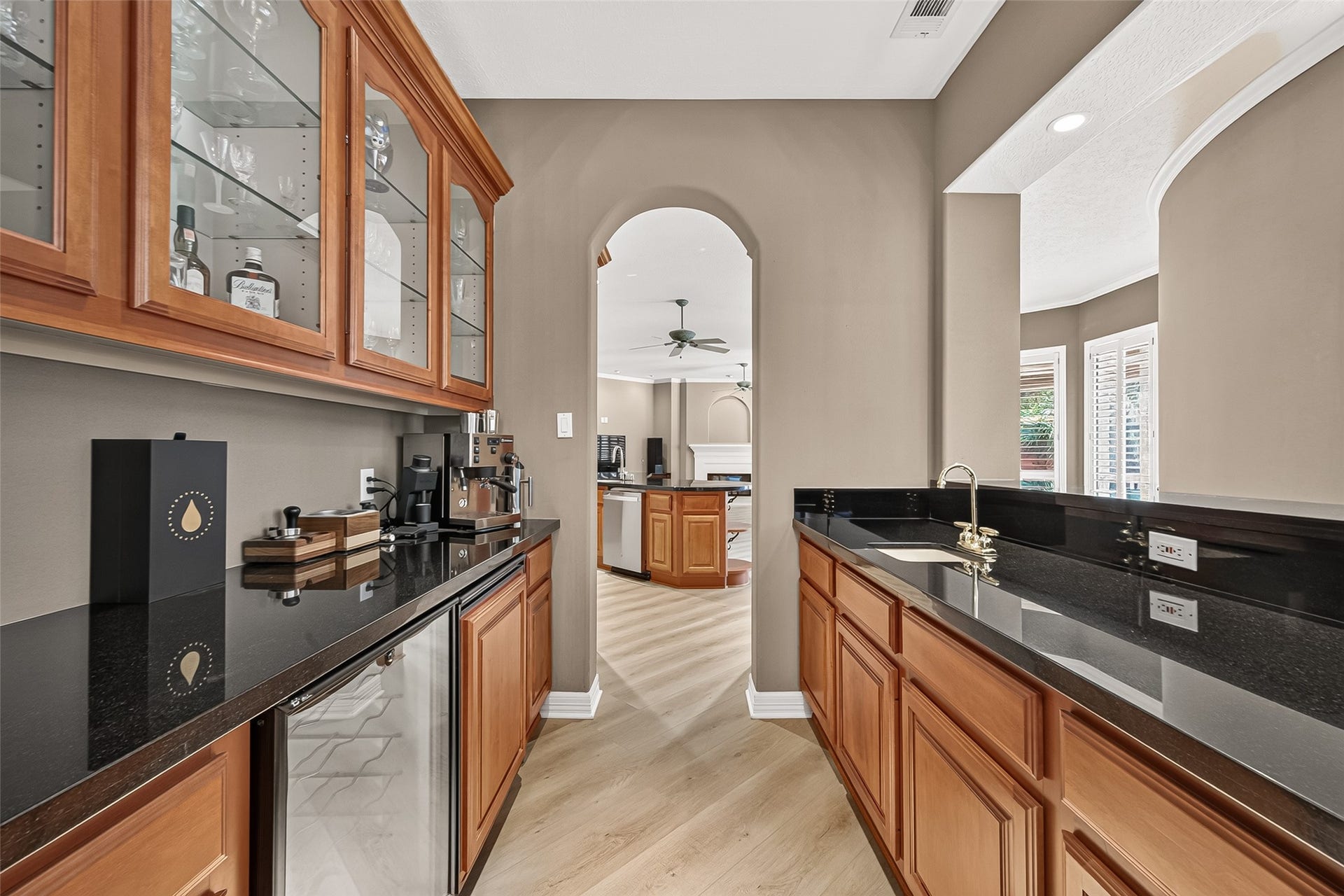 63 Harbor View Drive, Sugar Land, TX 77479 Amazing wet bar with rich wood cabinetry, sleek black countertops, and glass display cabinets, perfect for entertaining and enhancing your living space. Located right off the formal dining, kitchen, and sitting area, this space is perfect for entertaining!