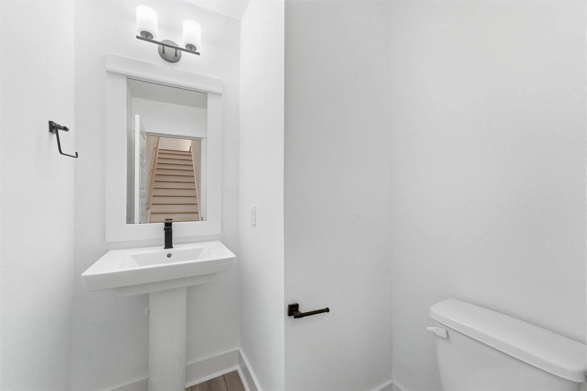 Half bath with a pedestal sink and modern matte black fixtures.