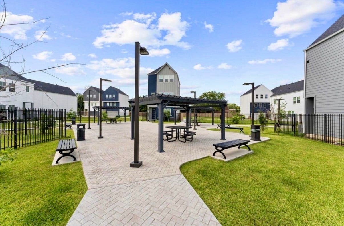 Community park with pergolas, picnic tables, benches, and green space, just steps from home.