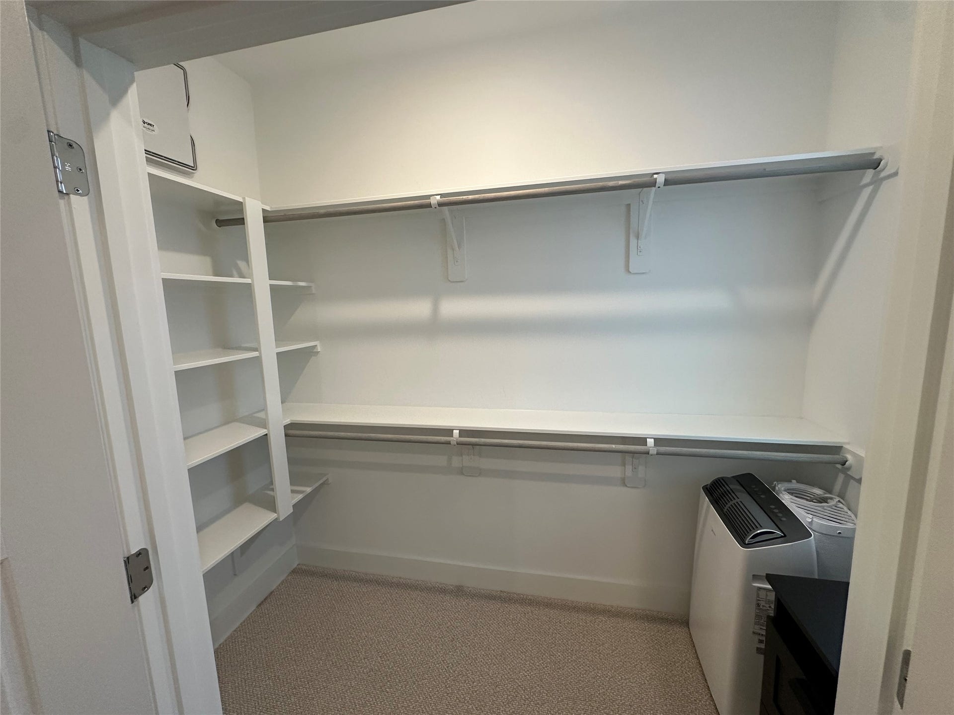 Spacious primary walk-in closet with double hanging rods and built-in shelving.