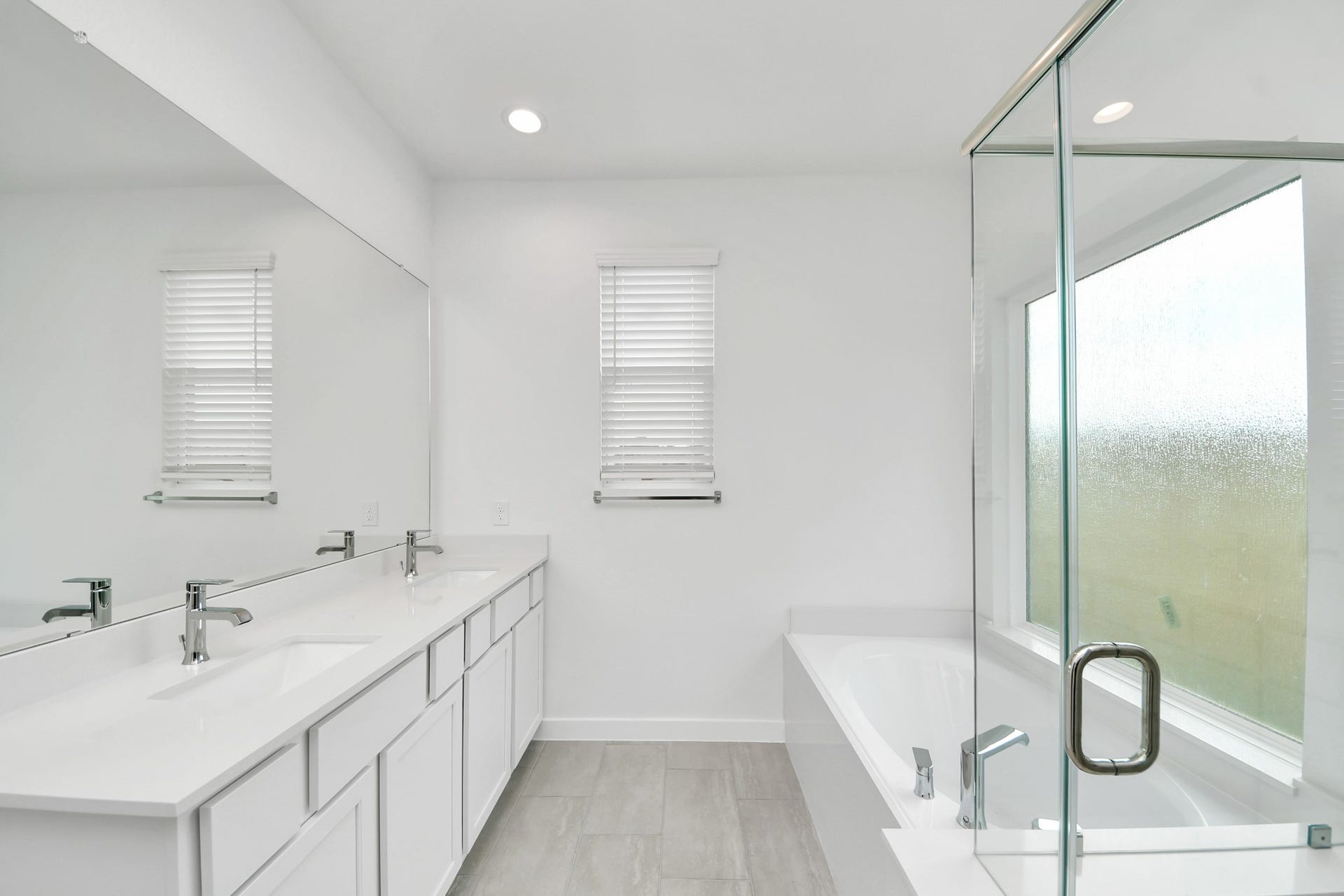5814 Madison Trail Drive, Richmond, TX 77469 Escape to a spa-like oasis in this primary bathroom. Enjoy a walk-in shower with tile surround, a separate garden tub with custom detailing, and an elegant vanity featuring light countertops, modern hardware, and beautiful vanity lights. Experience luxury and relaxation in every detail. Sample photo of completed home with similar floor plan. Actual colors and selections may vary.