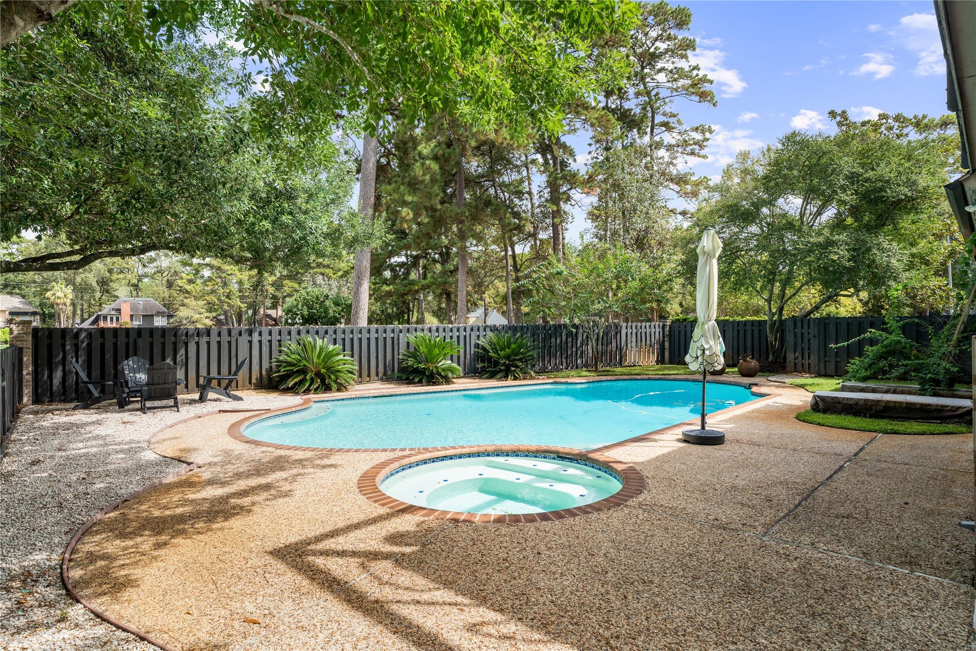 4719 Breezy Point Drive, Houston, TX 77345 The private backyard showcases a resort style pool and spa surrounded by mature trees and lush landscaping, with generous poolside space for lounge seating, entertaining, and soaking up the sun.