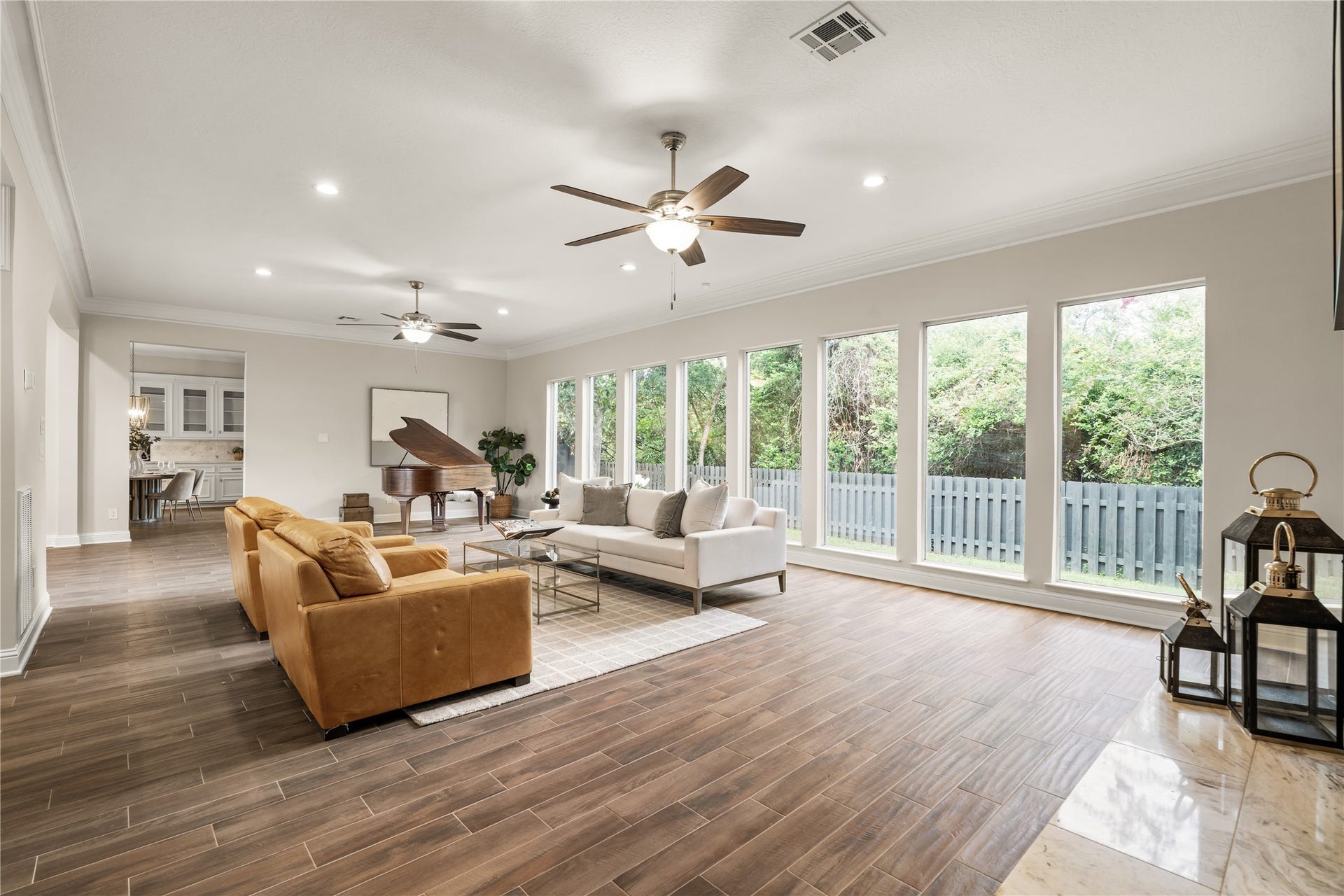 4719 Breezy Point Drive, Houston, TX 77345 A dramatic wall of windows bathes the expansive living room in natural light, creating an airy, sophisticated setting with beautiful views of the surrounding greenery.