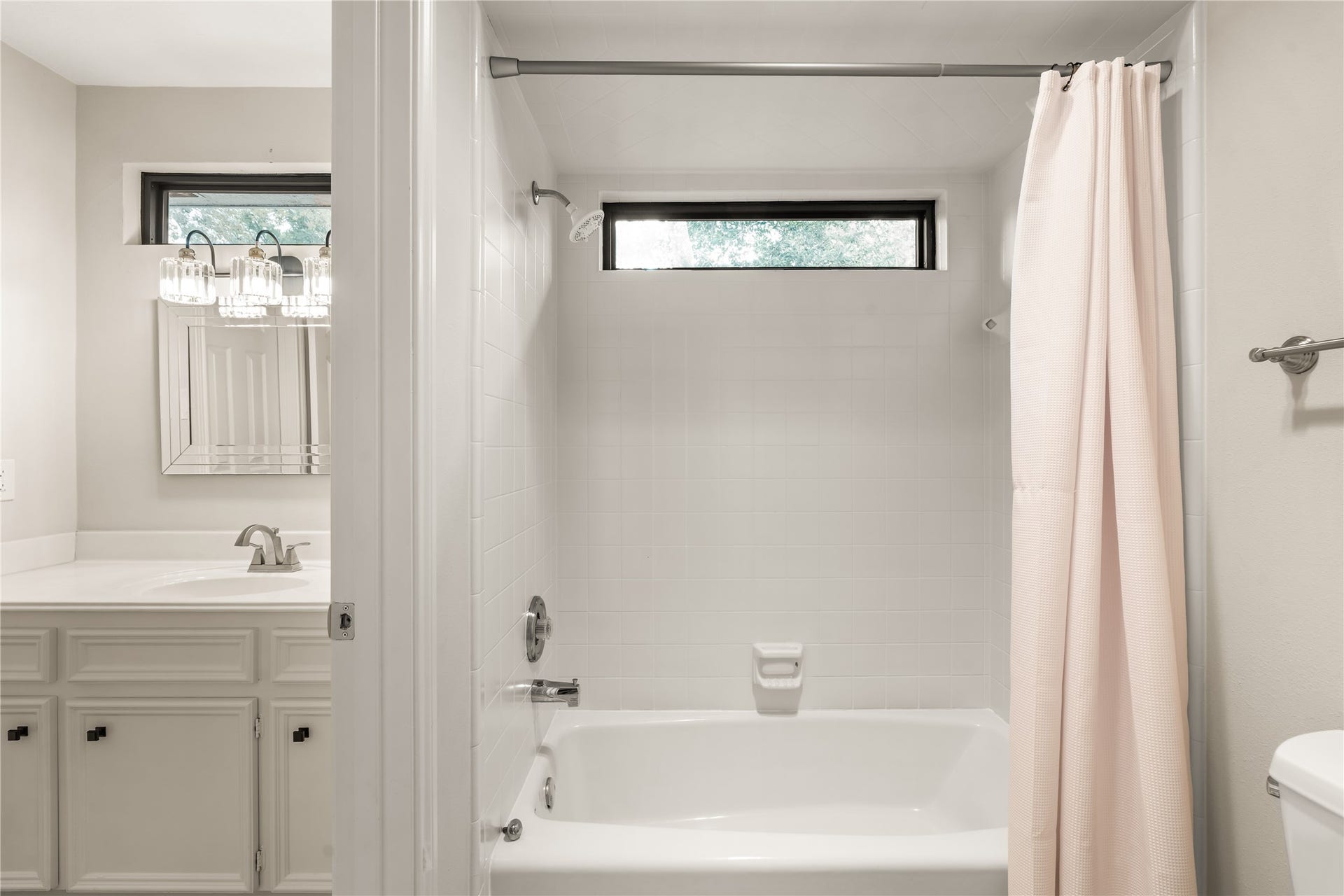 4719 Breezy Point Drive, Houston, TX 77345 A bright secondary bath features a tub-and-shower combination, crisp tile surround, natural light, and a spacious vanity for comfortable everyday use.