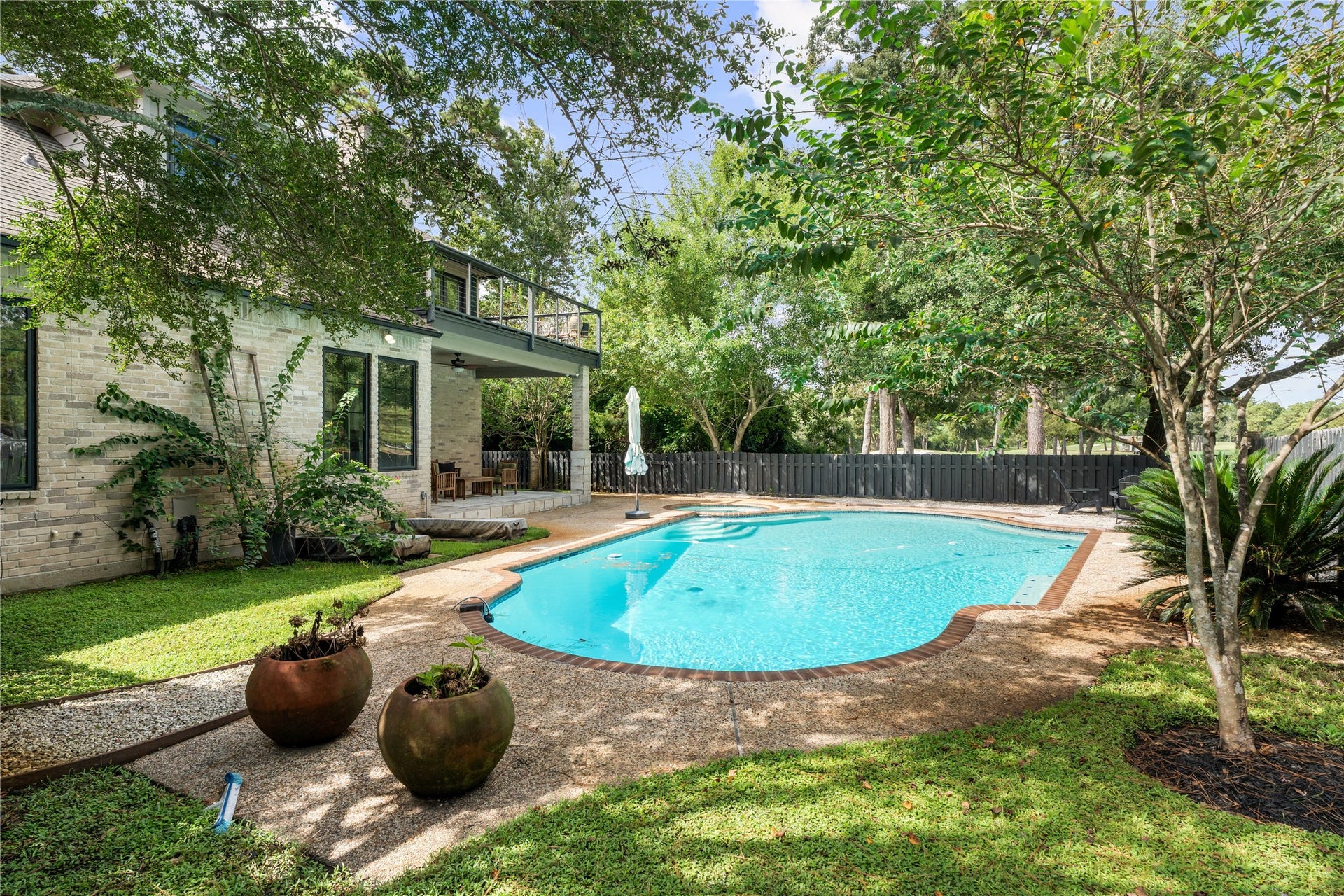 4719 Breezy Point Drive, Houston, TX 77345 Lush greenery and mature trees surround the pool and spa, creating a private outdoor retreat with multiple areas for lounging, entertaining, and enjoying the comfort of no side neighbors.