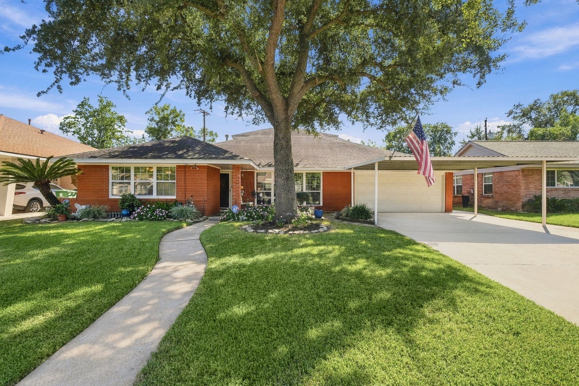5125 Nina Lee Lane, Houston, TX 77092 Charming brick home with a welcoming front porch, lush landscaping, and a spacious driveway.