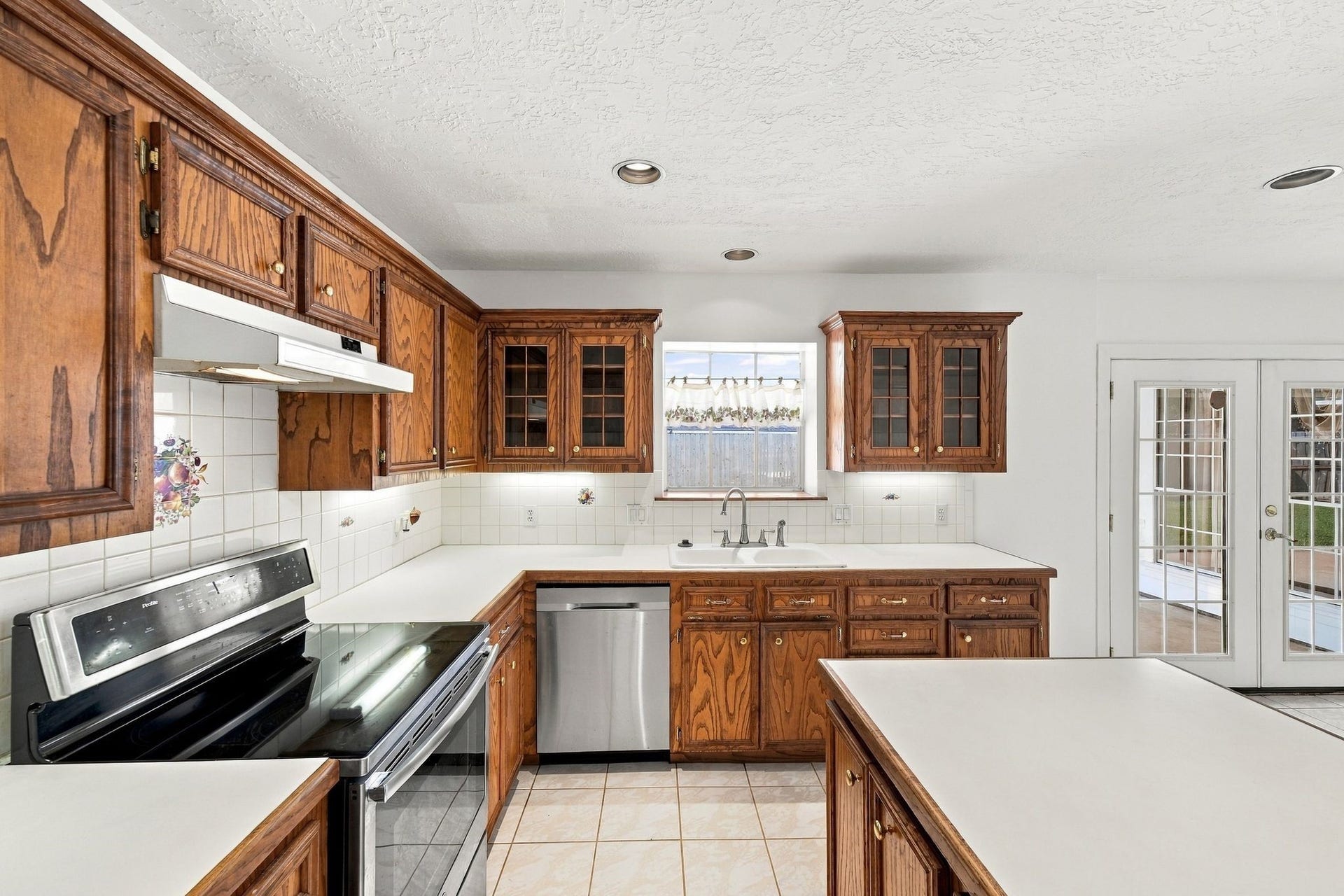 5125 Nina Lee Lane, Houston, TX 77092 Charming kitchen with rich wooden cabinetry, modern stainless steel appliances, and ample counter space, leading to bright French doors opening to the backyard.