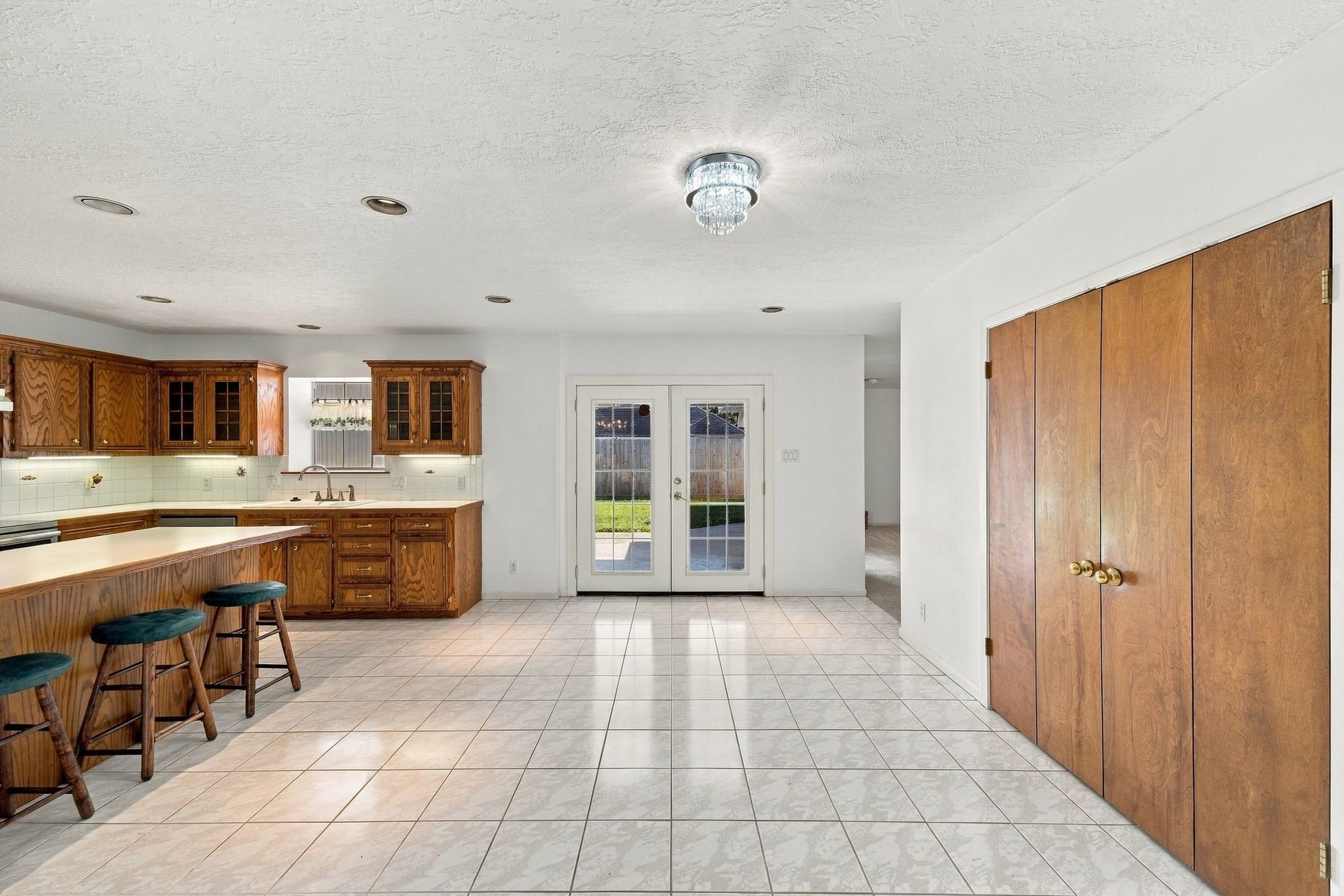 5125 Nina Lee Lane, Houston, TX 77092 Spacious kitchen with classic wood cabinetry, stainless steel appliances, and a central island with seating. Bright and airy, featuring French doors leading to the backyard, perfect for entertaining.
