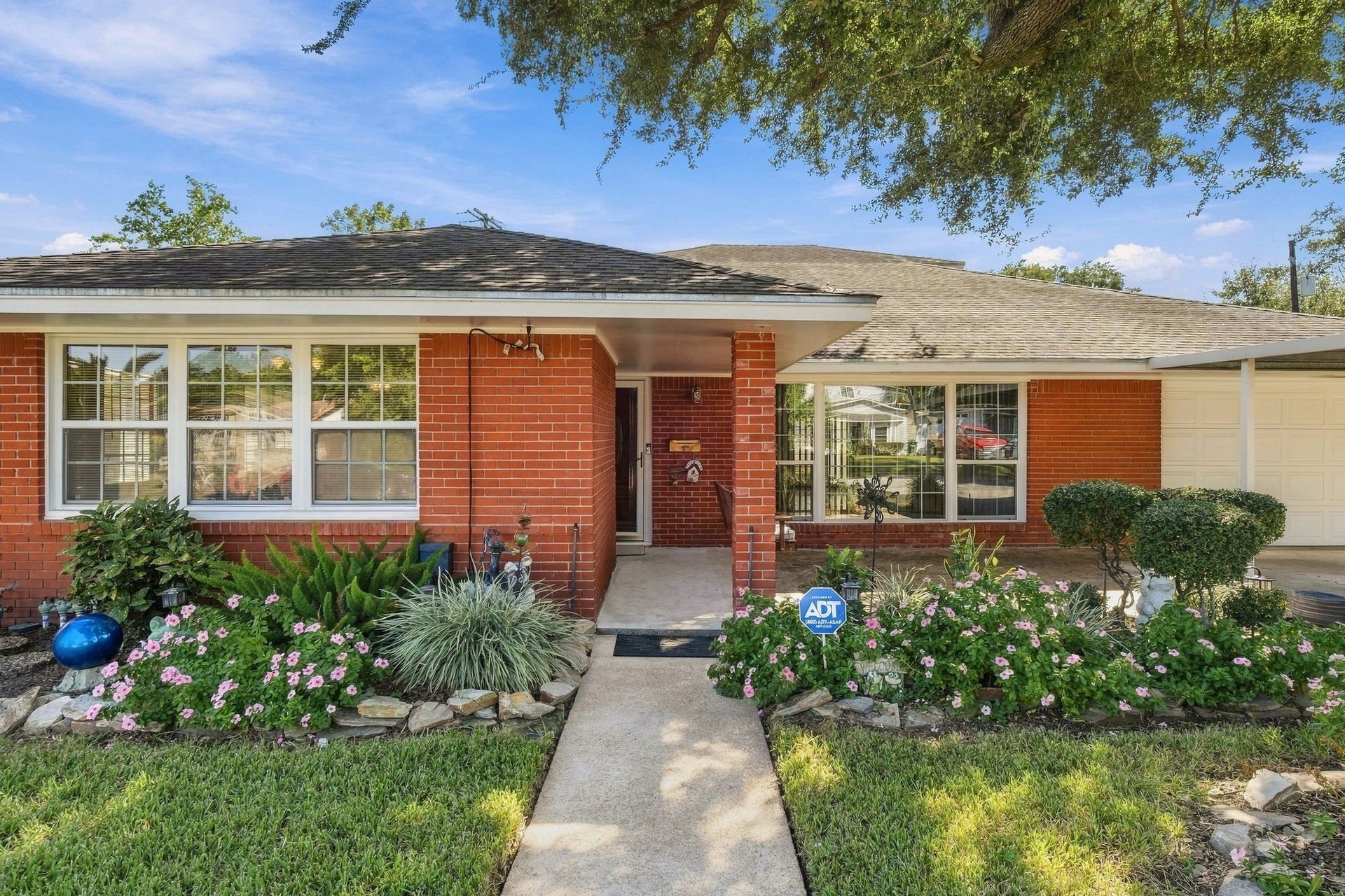 5125 Nina Lee Lane, Houston, TX 77092 Classic brick home with a welcoming front patio featuring a cozy swing and large windows inviting natural light.