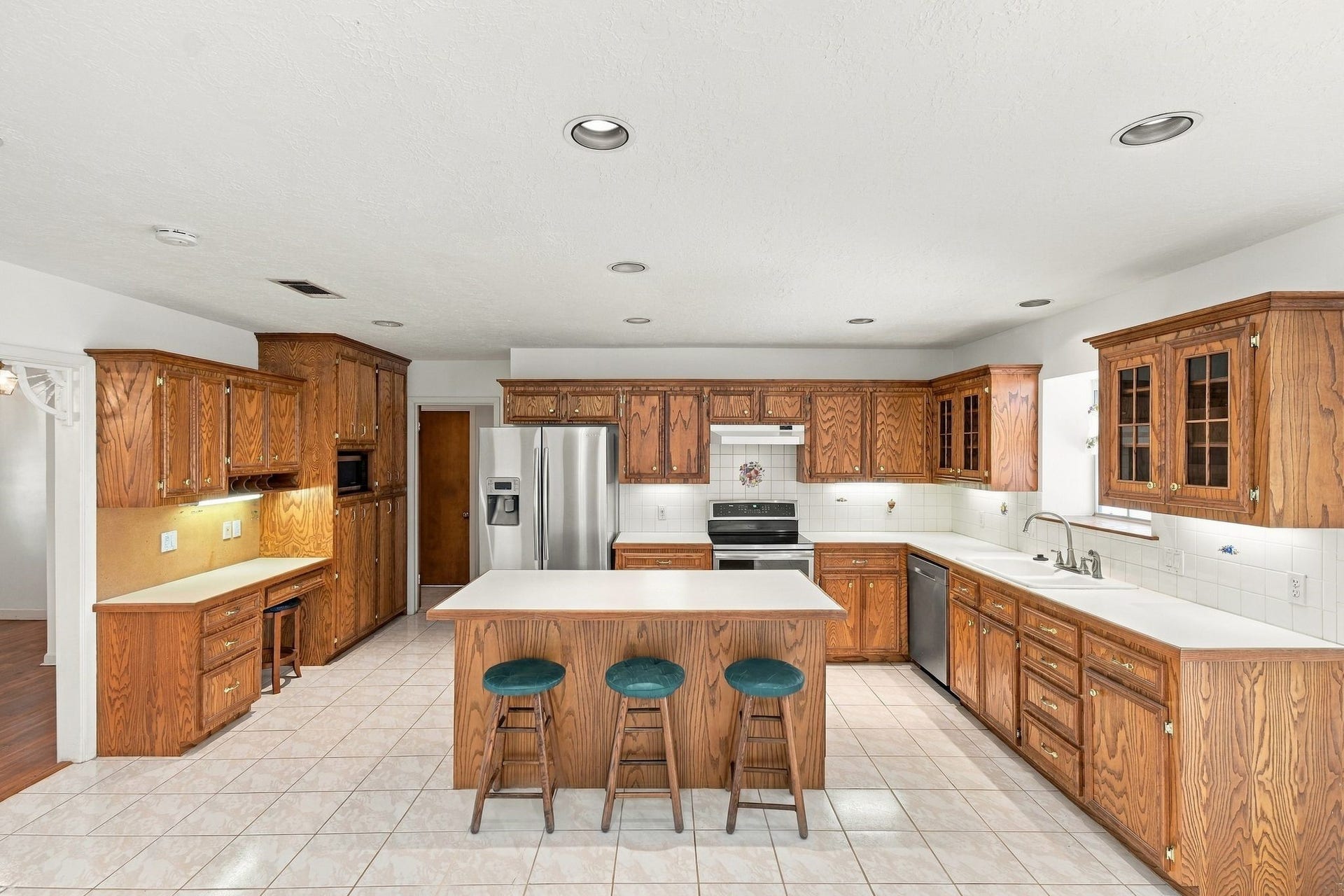 5125 Nina Lee Lane, Houston, TX 77092 Gourmet kitchen and dining area featuring elegant wooden cabinetry, a large breakfast bar with seating, and ample natural light from patio doors leading to the backyard.